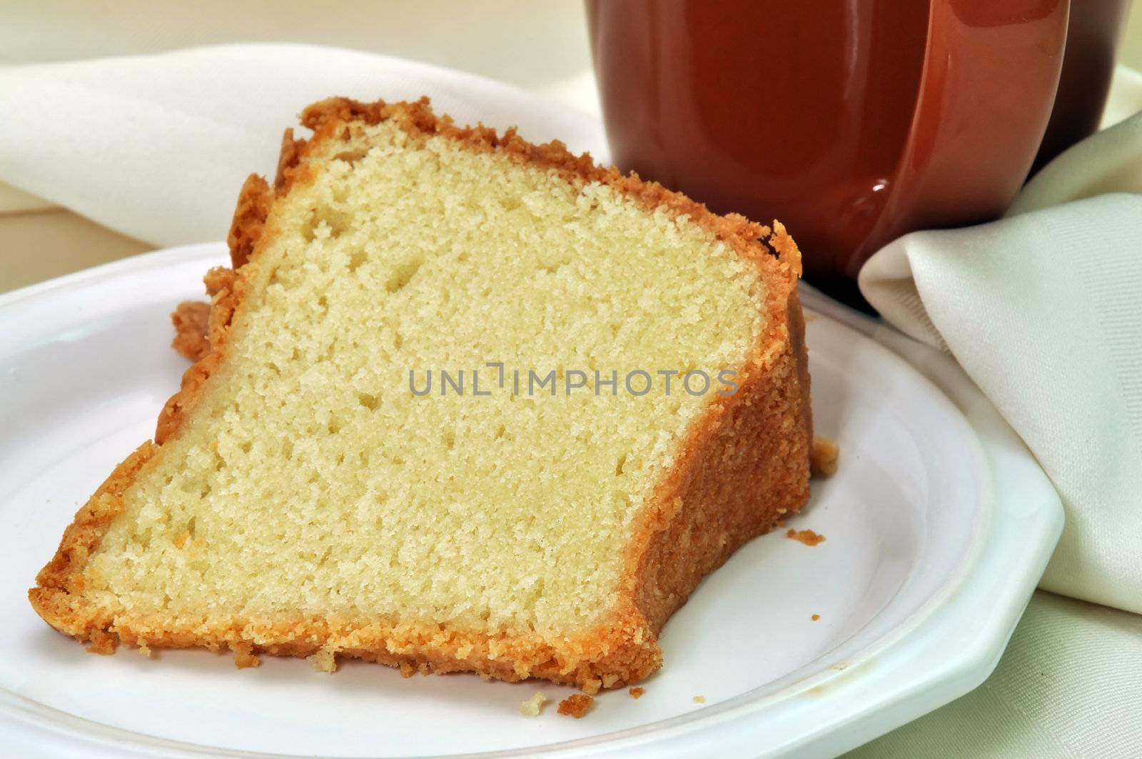 Closeup of pound cake with napkin and cup of coffee in background.