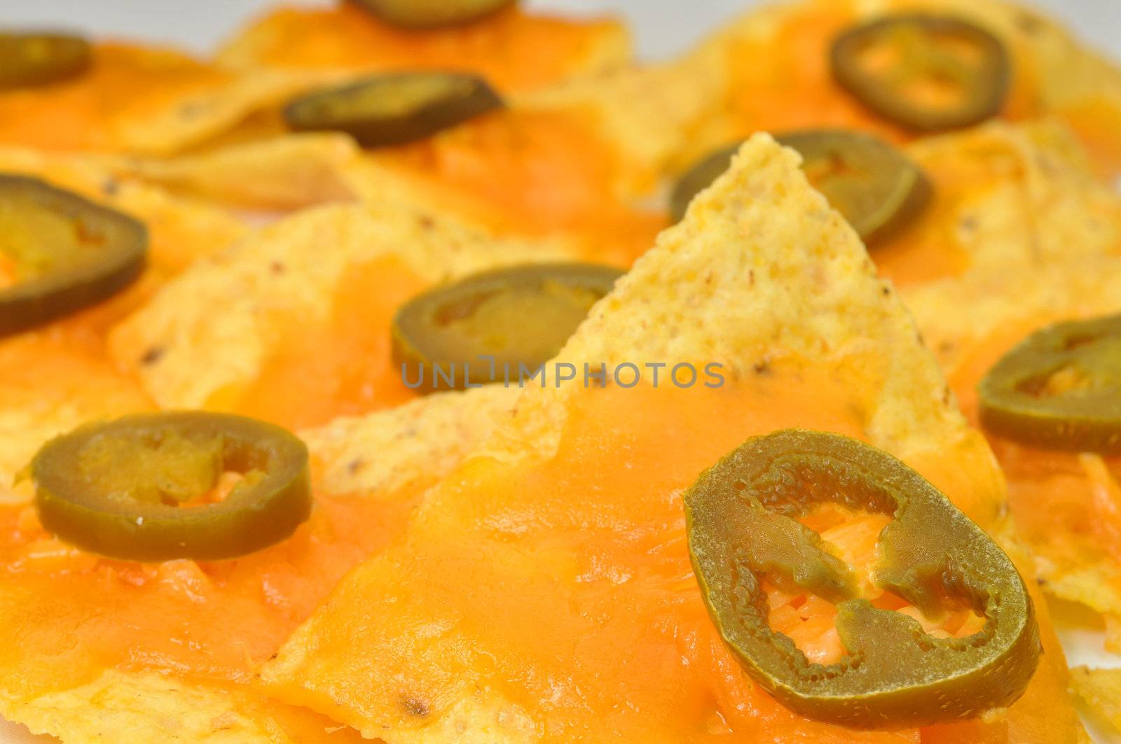 Focus on one nacho on plate of nachos. 