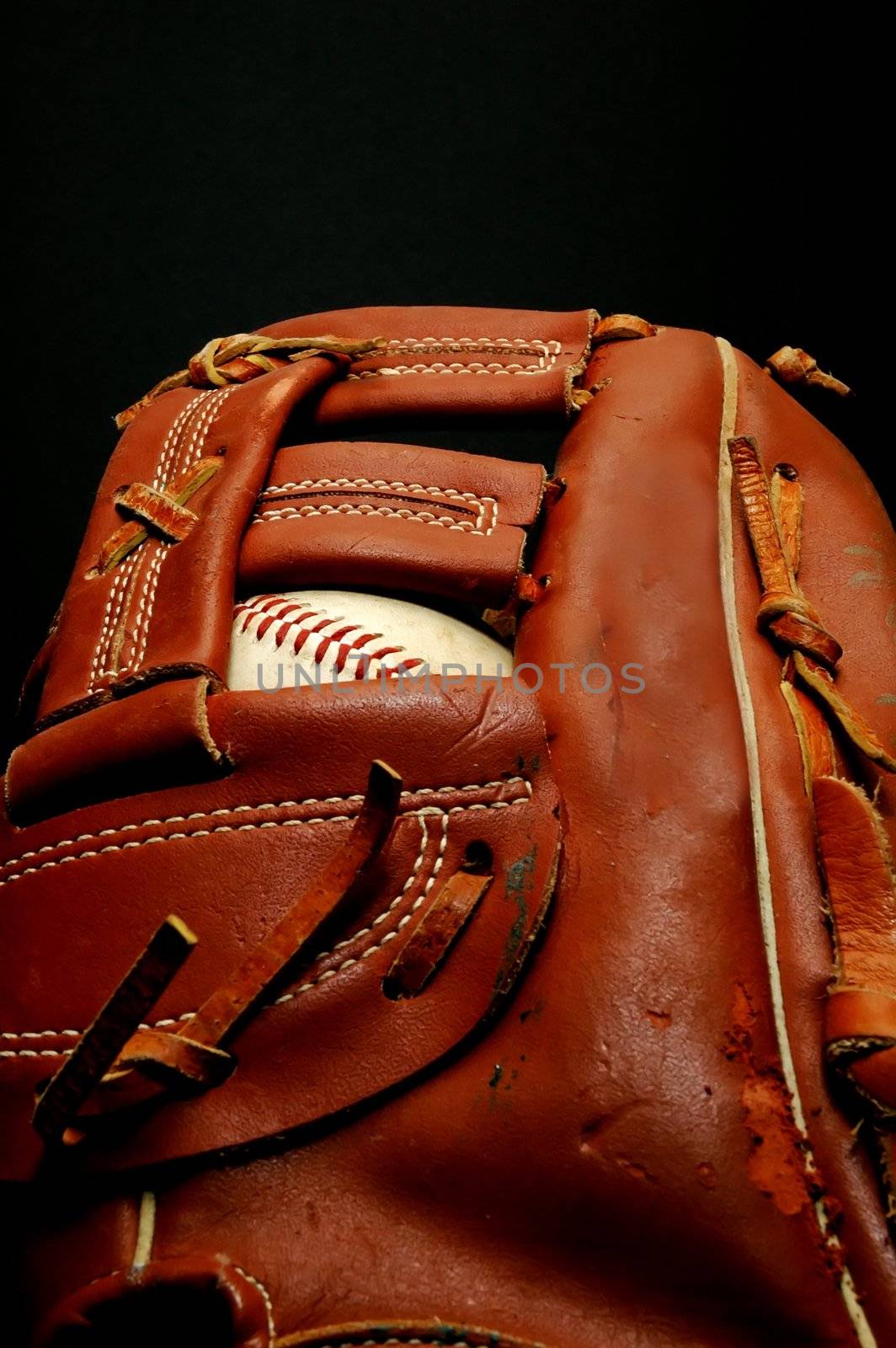 Baseball in glove on black background