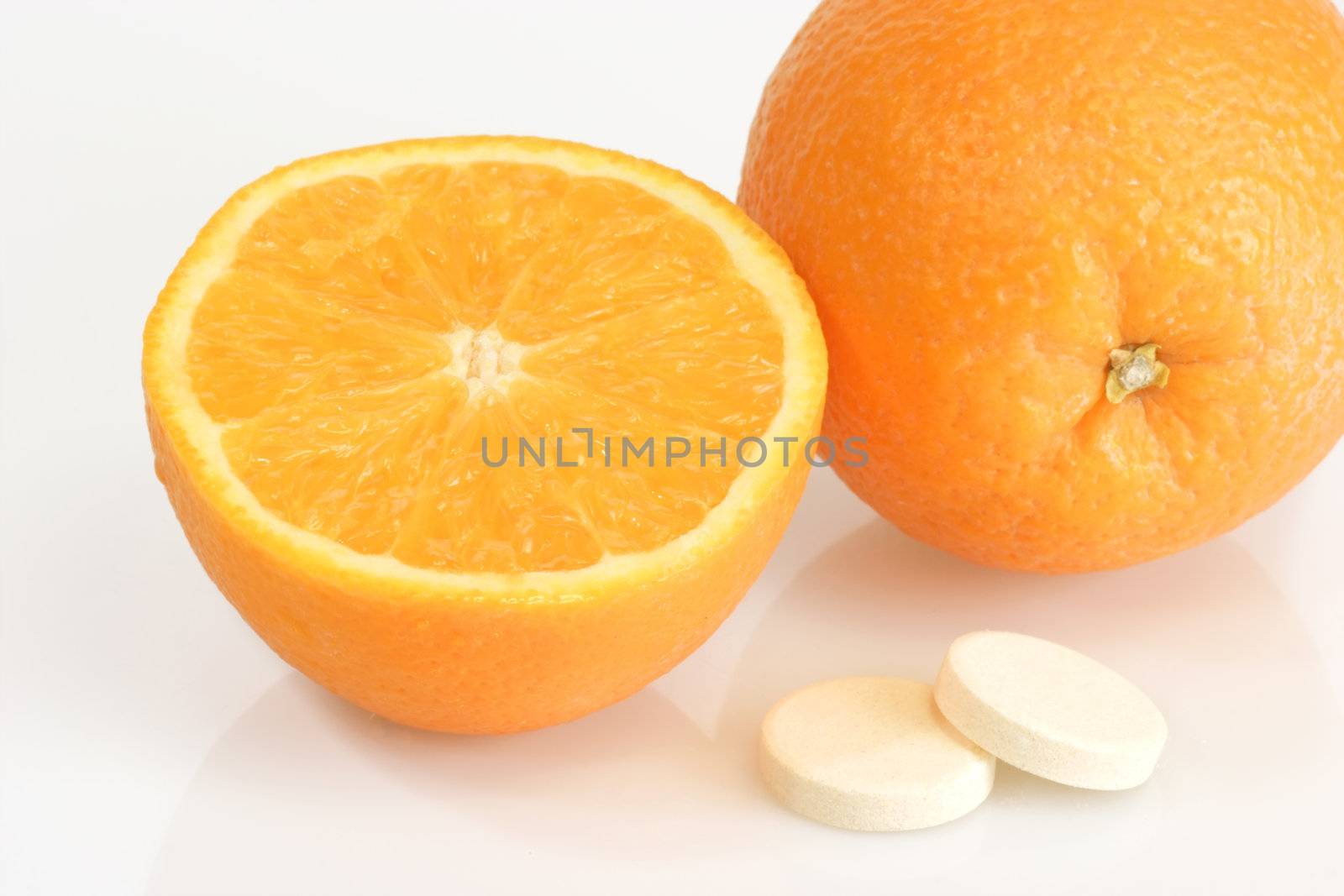Large pills with orange fruits tube on bright background
