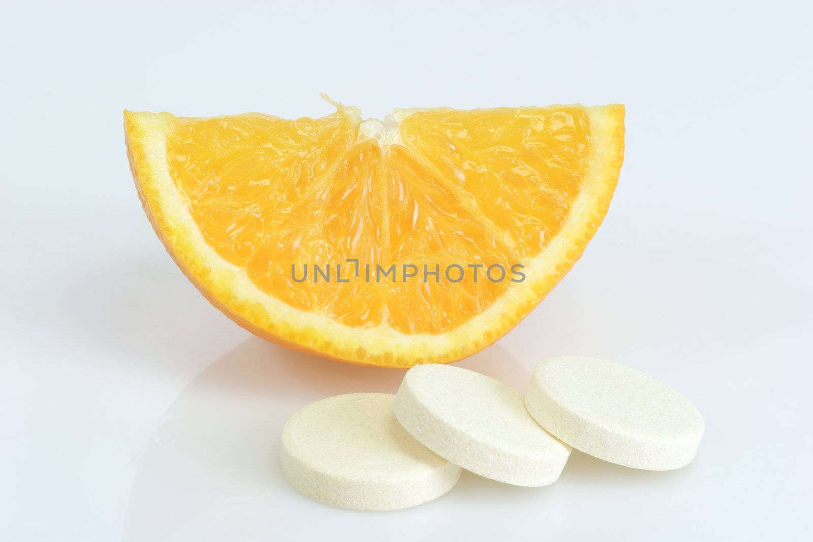 Large pills with orange fruits tube on bright background