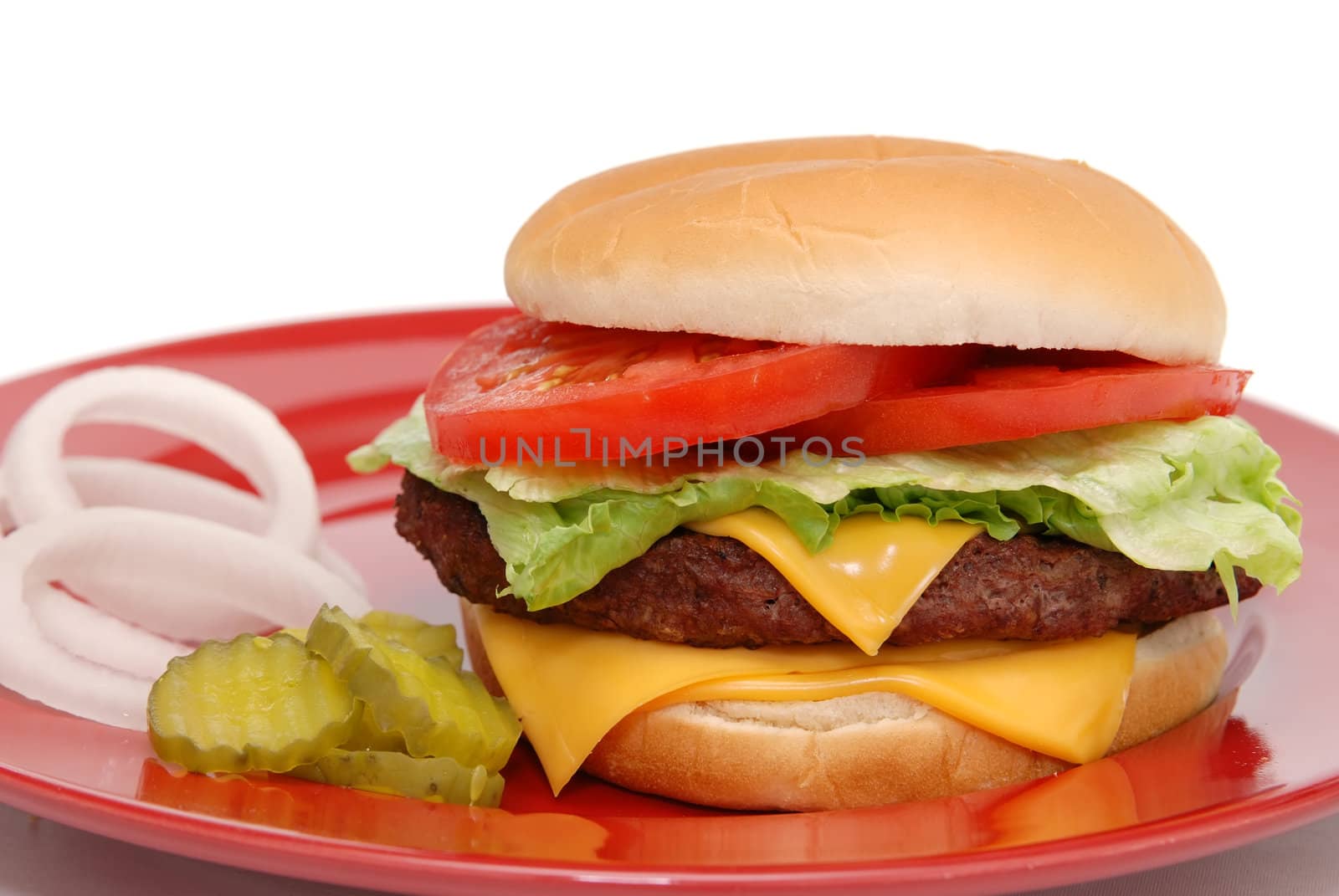 Cheeseburger with pickles and onions on red plate.  Isolated on white background.