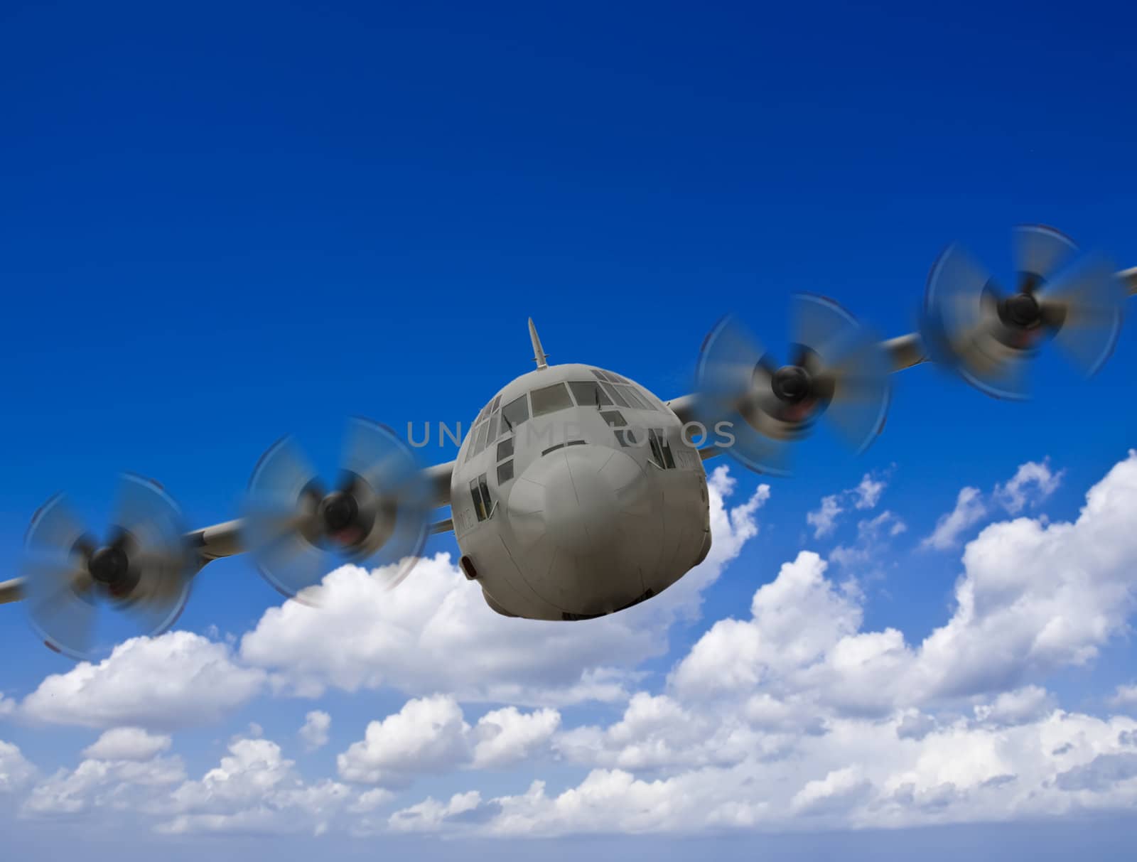 Military Hercules C130 aircraft in flight against a blue sky