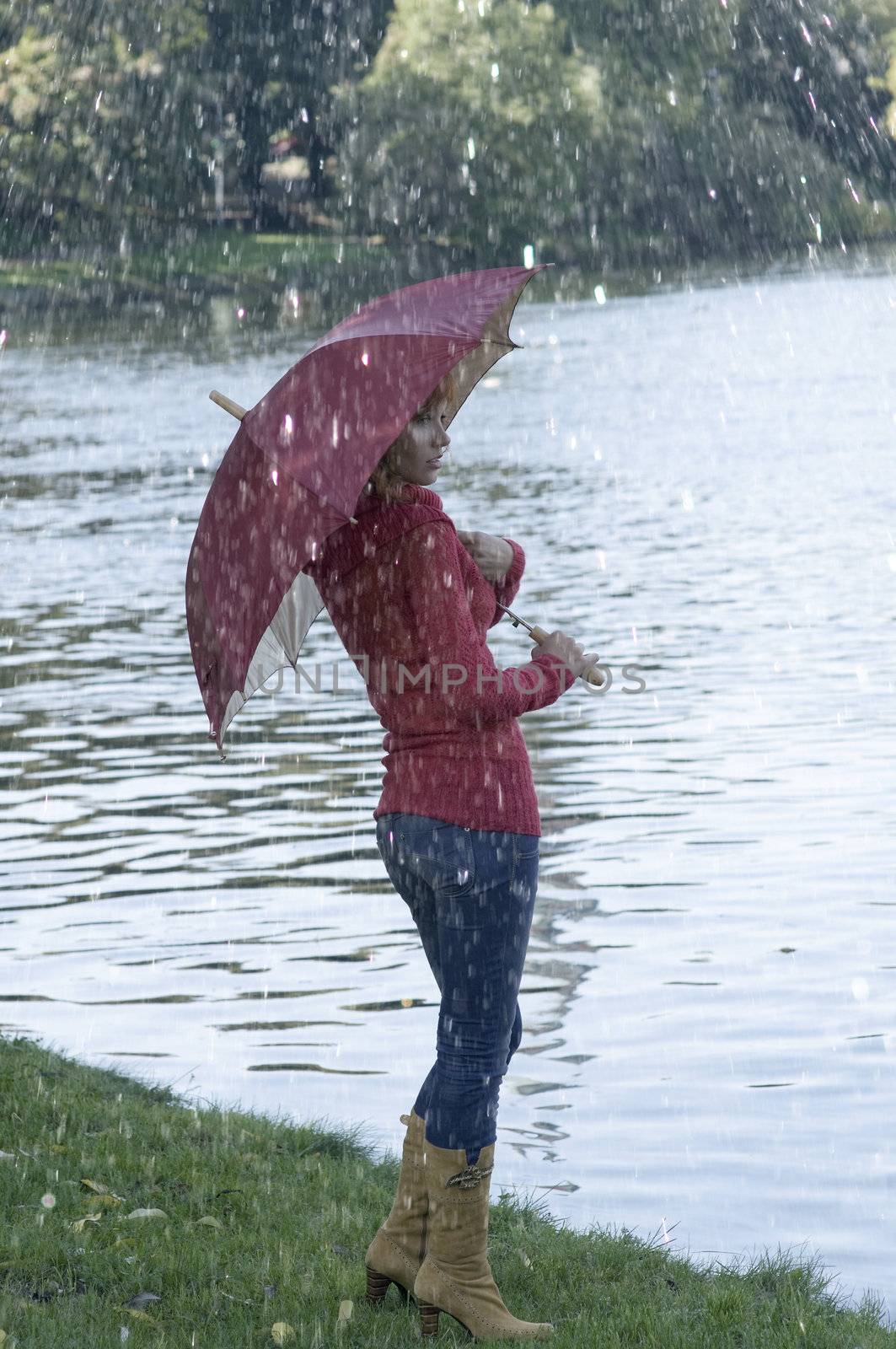 Cute girl with umbrella looking at the river in fall season