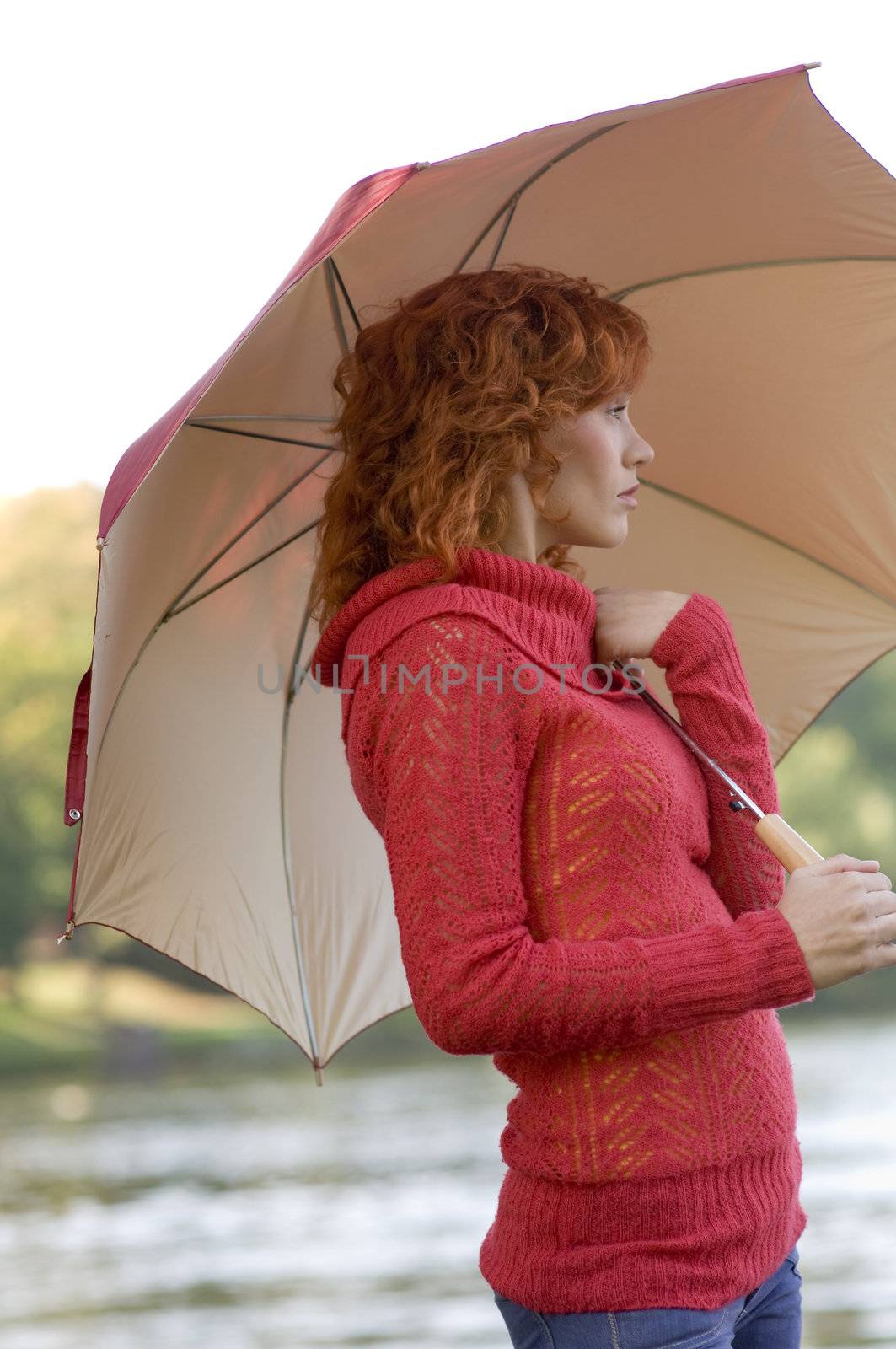 nice woman with umbrella looking thoughtful the river