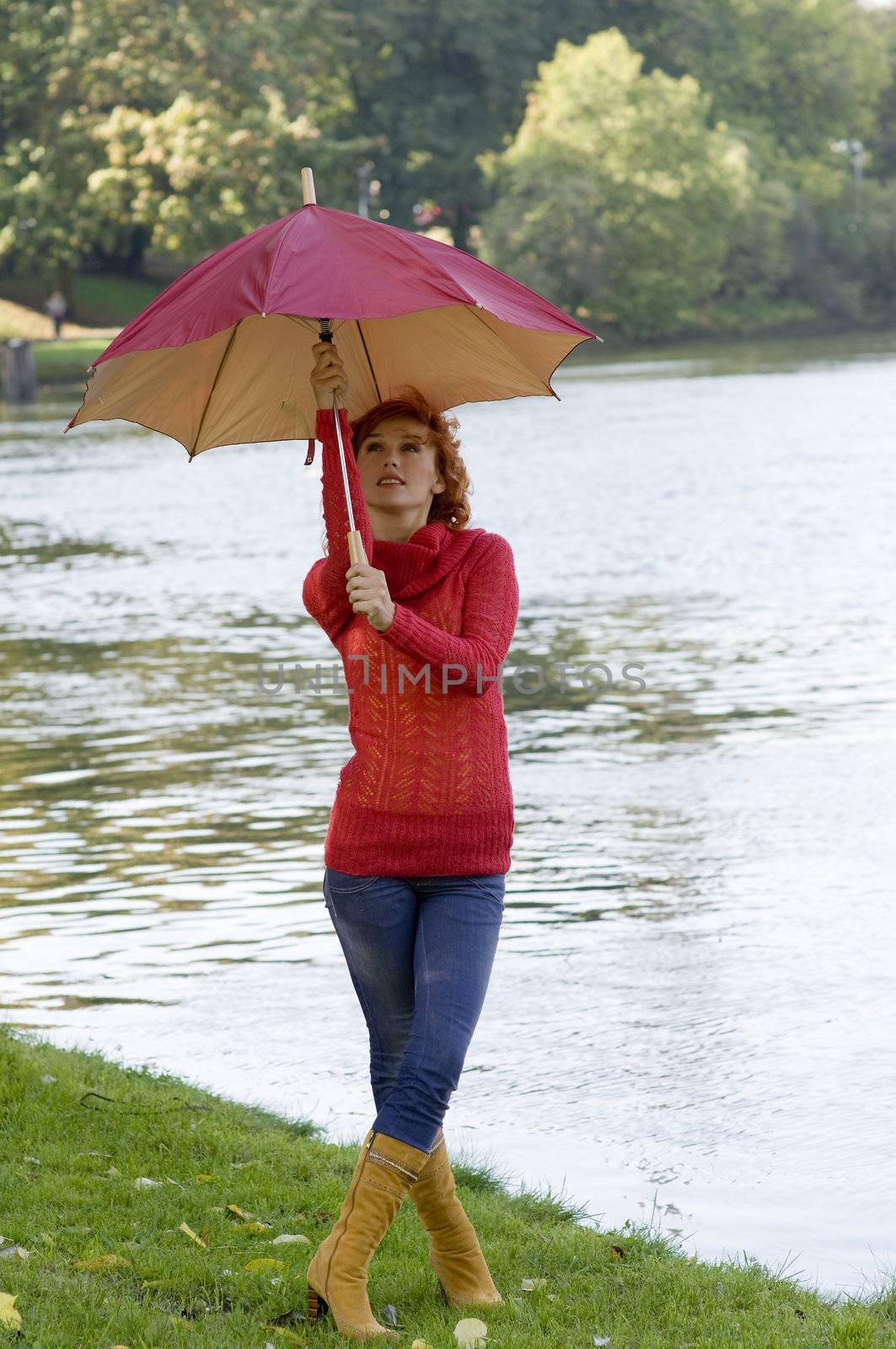 very nice girl closing her umbrella in park near a river