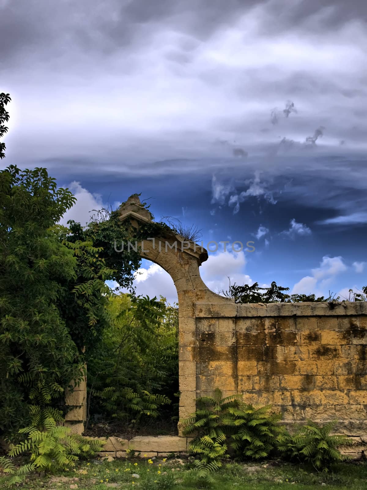 Archway leading to abandoned and disused medieval cemetery in HDR