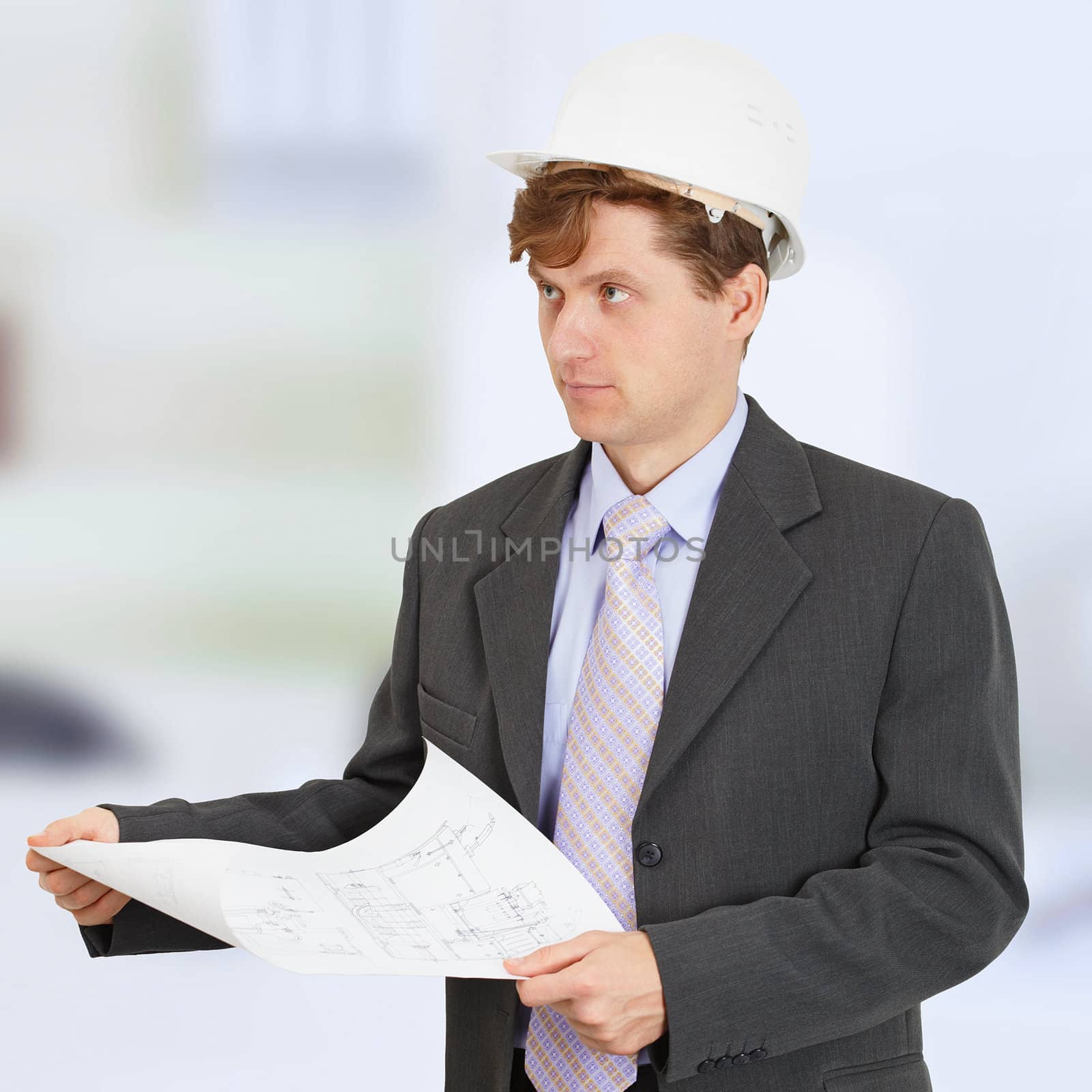 A man in a construction helmet with a drawing in the hands