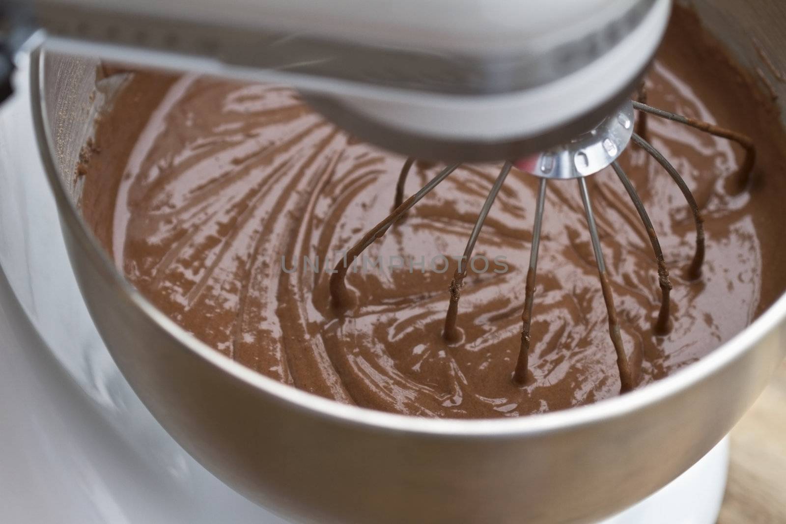 Abstract of chocolate cake batter being mixed in an electric mixer. Extreme shallow DOF with focus on wire mixer. 