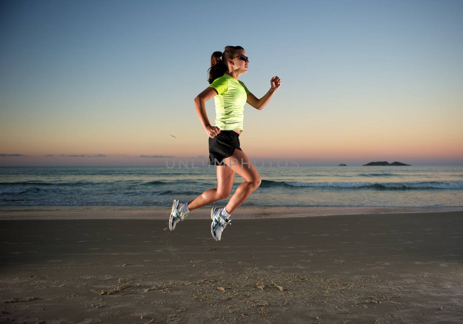 Woman doing exercises during sunset with sunglasses in Florianopolis, Santa Catarina, Brazil