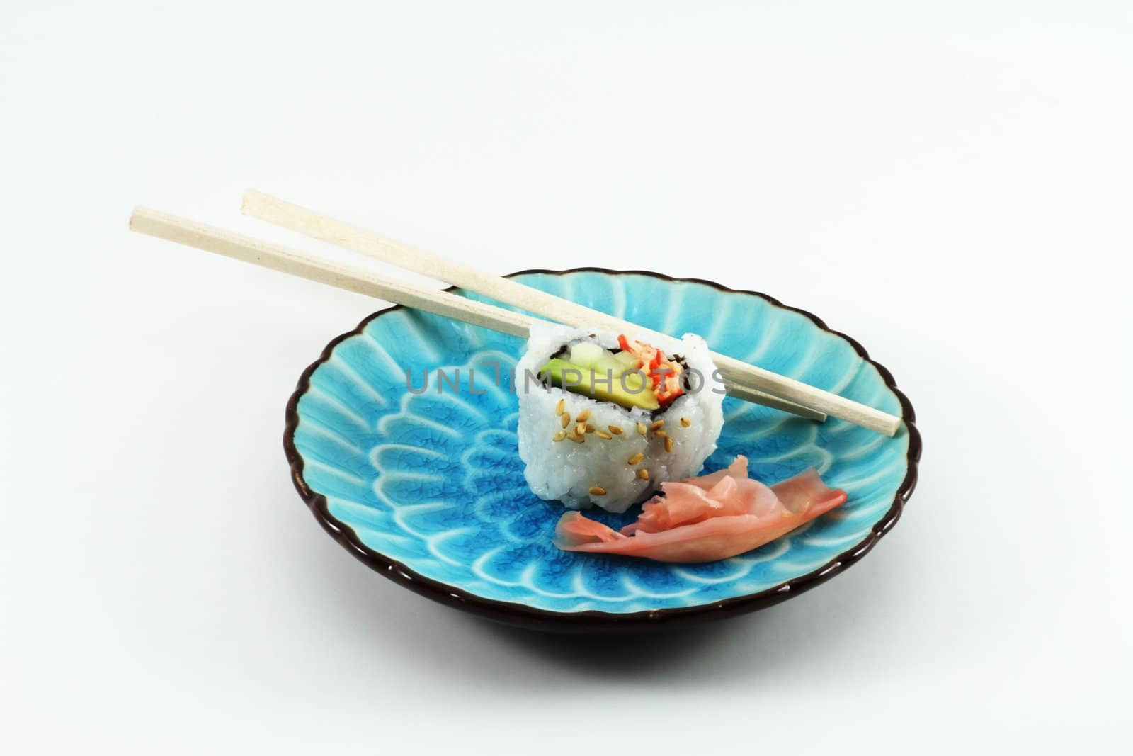 Far East table setting with chopsticks, sushi, and ginger root on a blue dish.