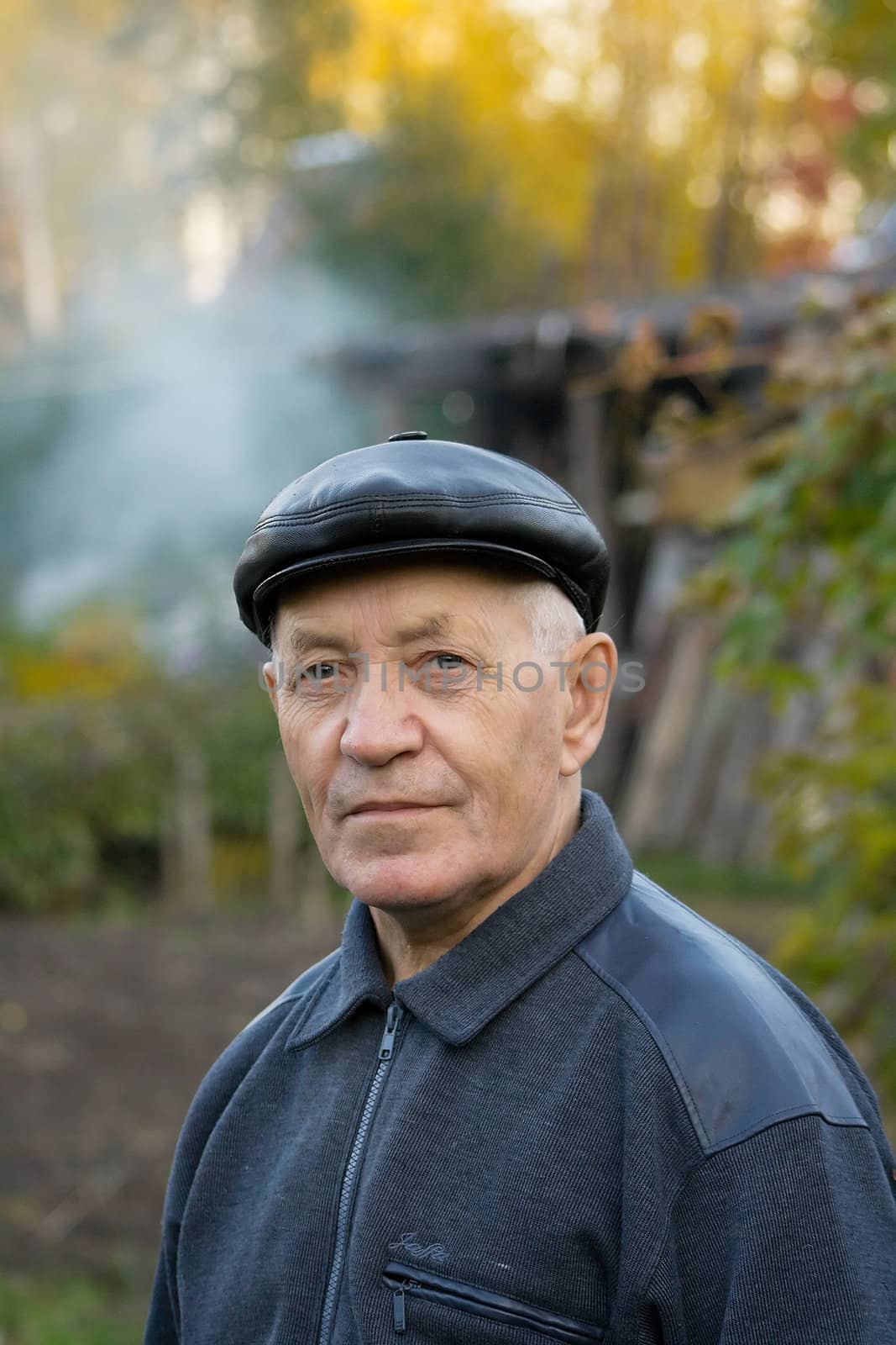 Portrait of the elderly man in a cap against the nature