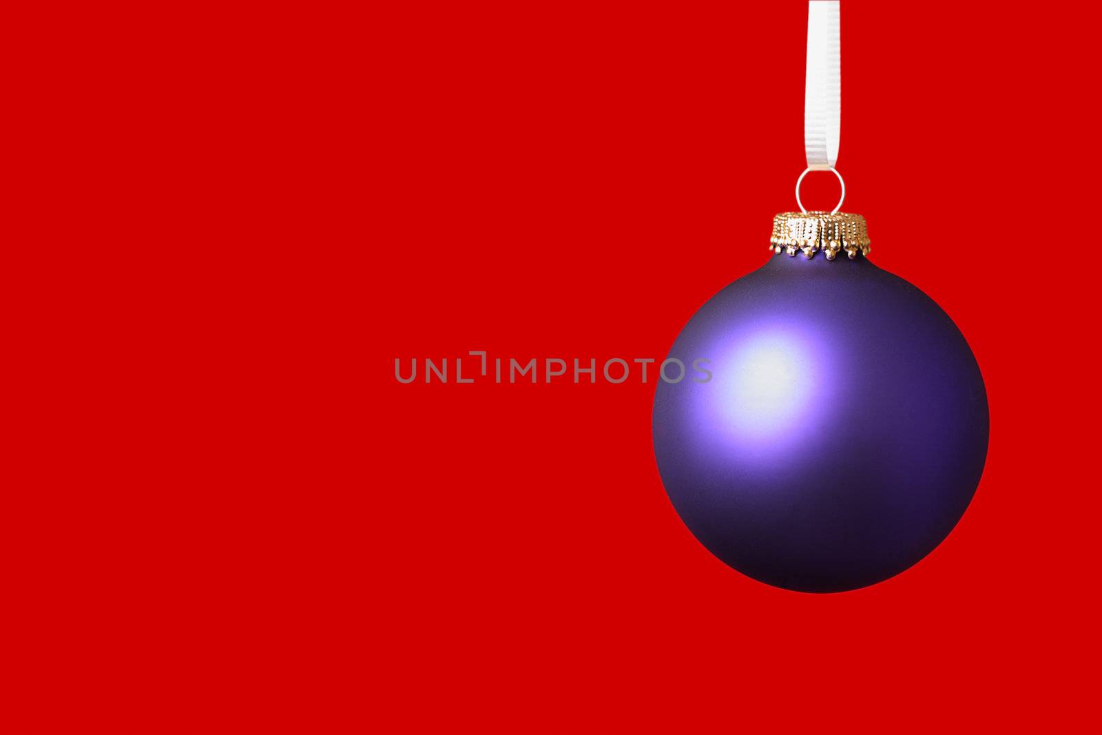 Purple christmas ornament haning on white ribbon on red background