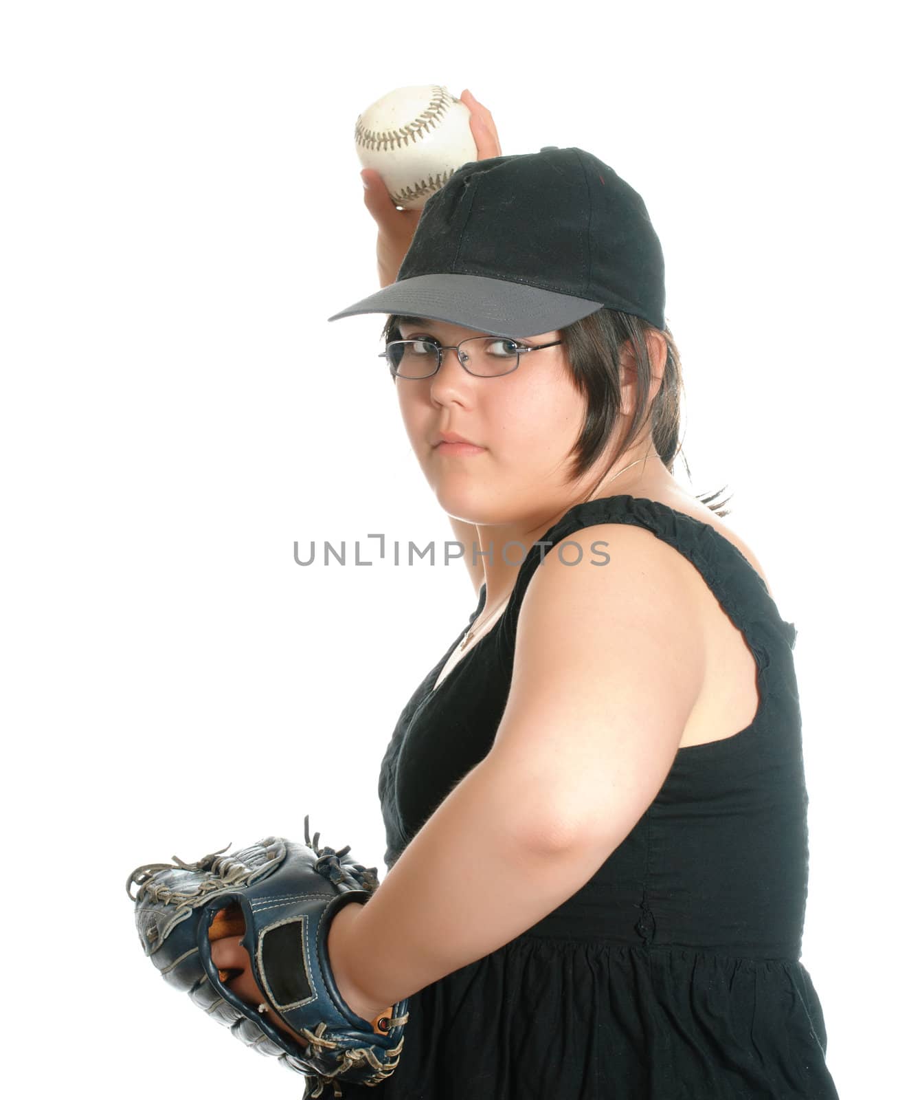 A young preteen girl wearing a baseball cap is in the process of pitching a baseball, isolated against a white background.