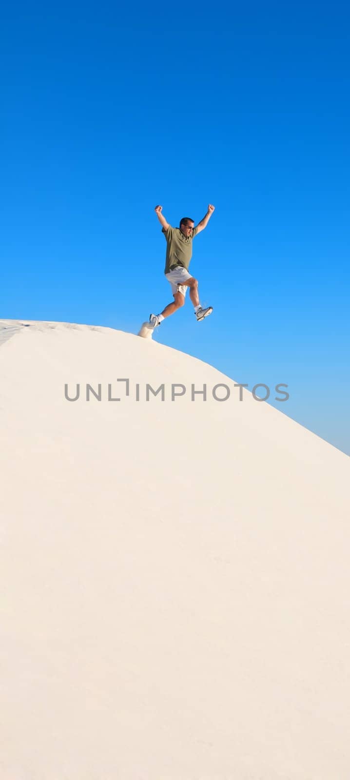 A man jumping off of a sand dune by Deimages