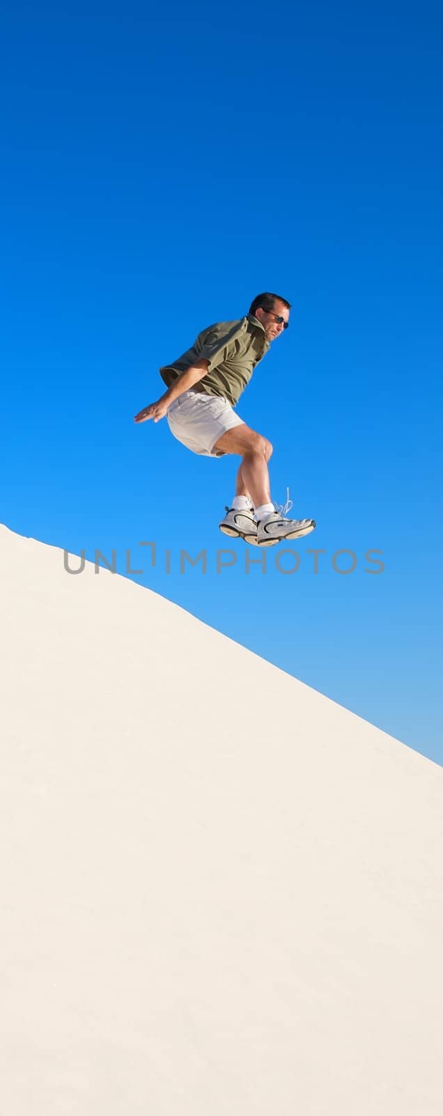 Man jumping off of sand dunes by Deimages