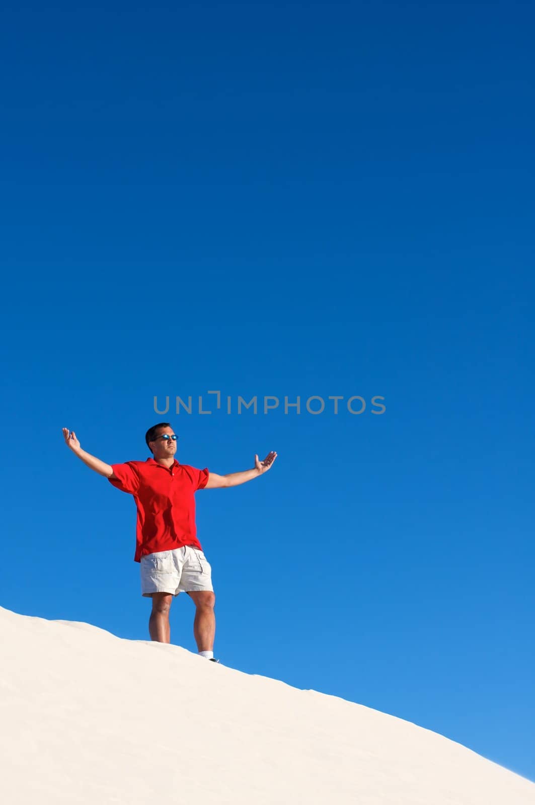 A man standing atop a sand dune by Deimages