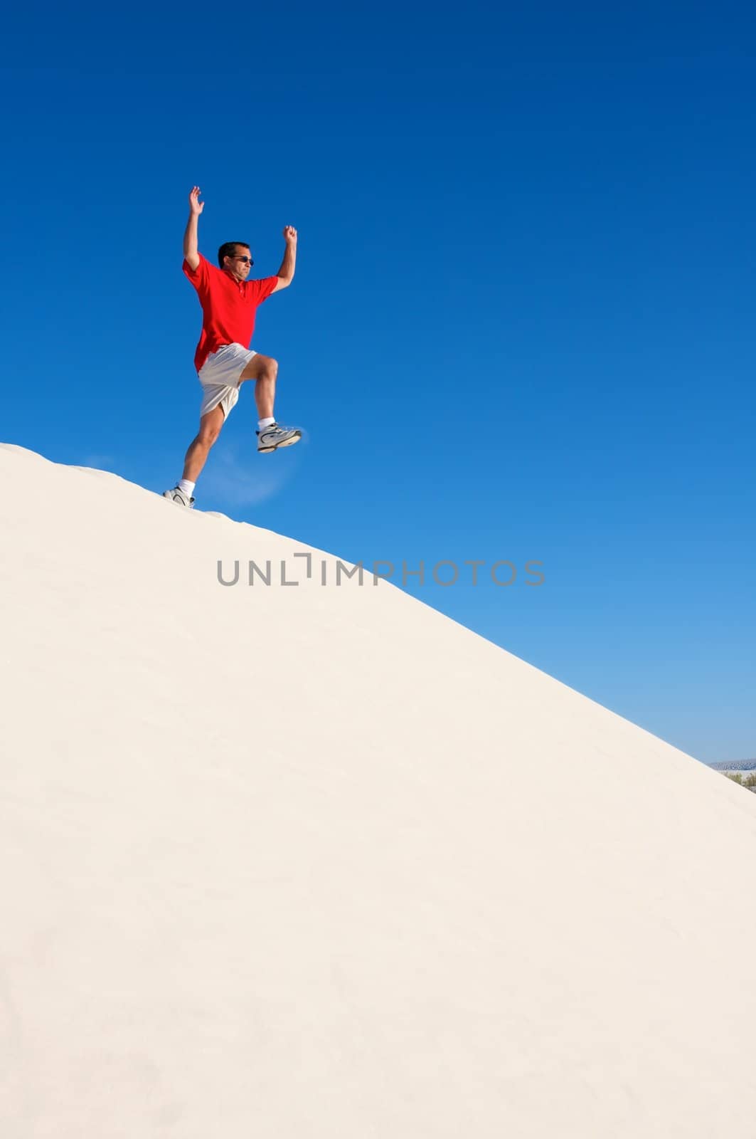 An image of a man jumping off a sand dune