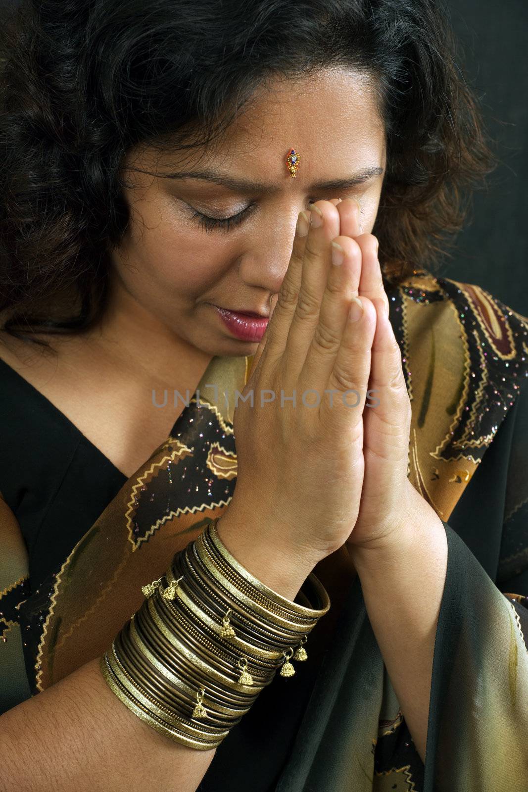 A beautiful Indian woman wearing a traditional sari and praying.
