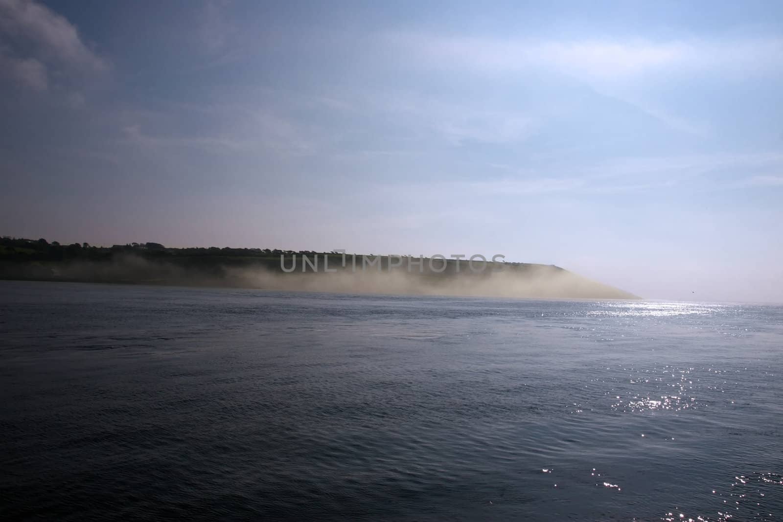 a calm sea on the west coast of ireland with a misty fog rolling in