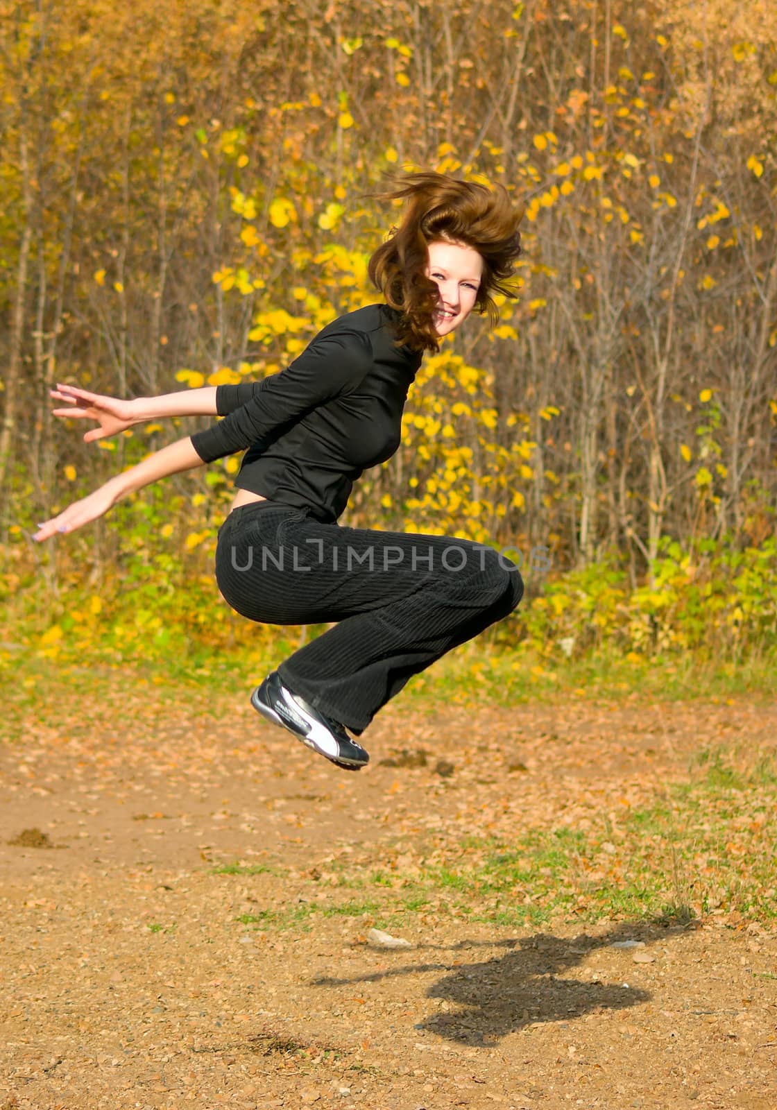 The jumping girl against the autumn nature
