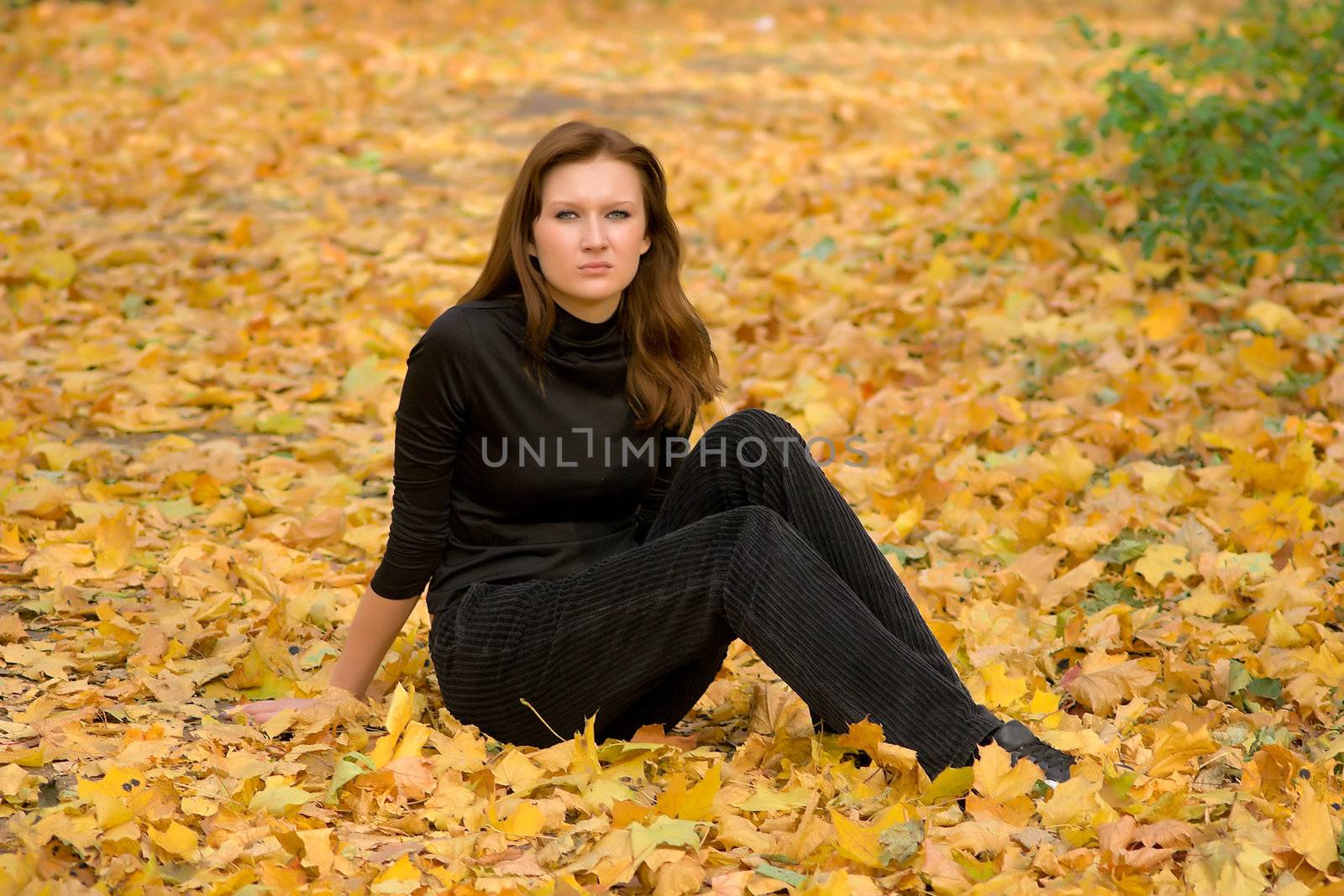 The sad young girl in autumn park during a leaf fall