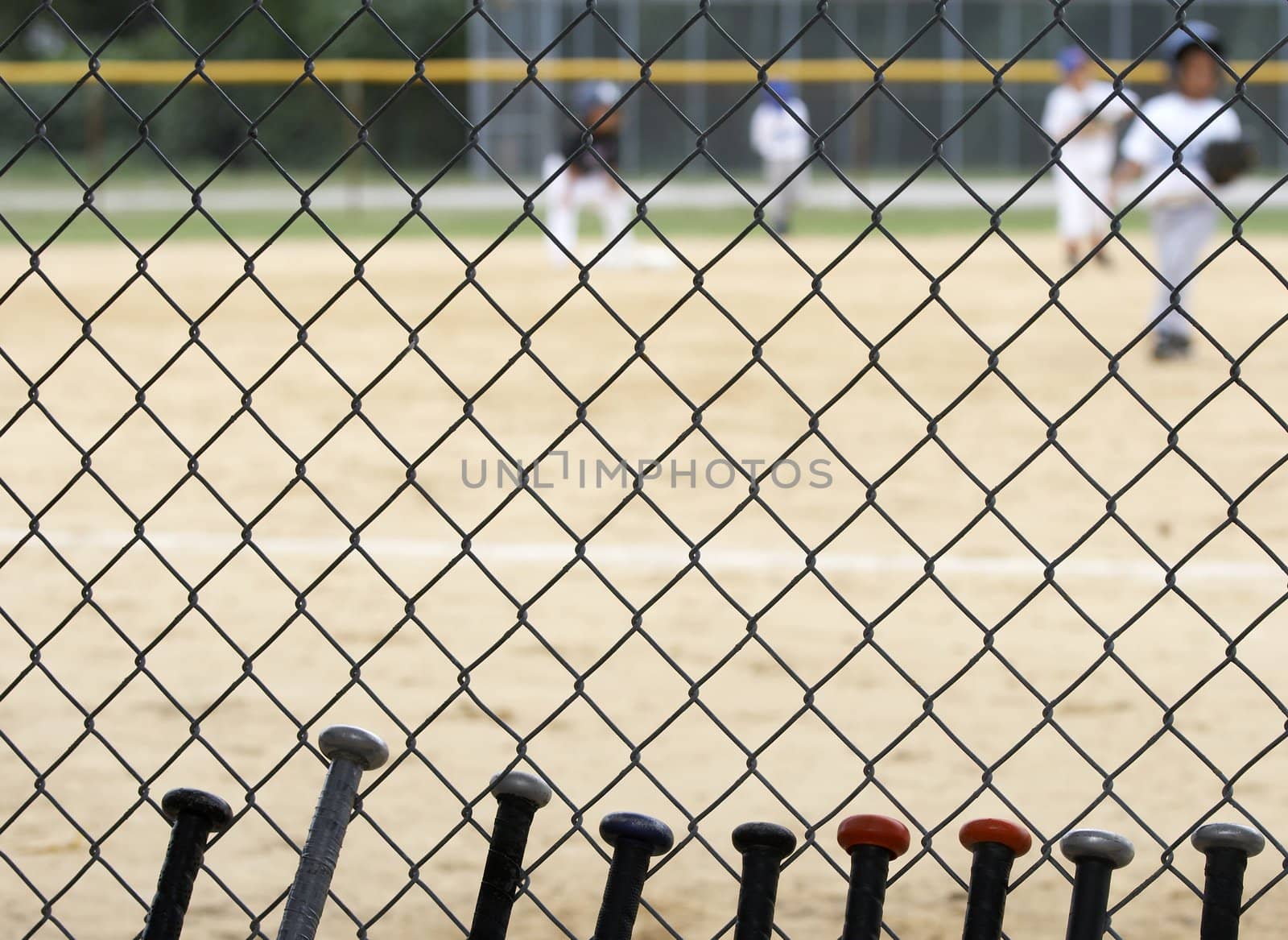 baseball bats learning against dugout fence as game is played