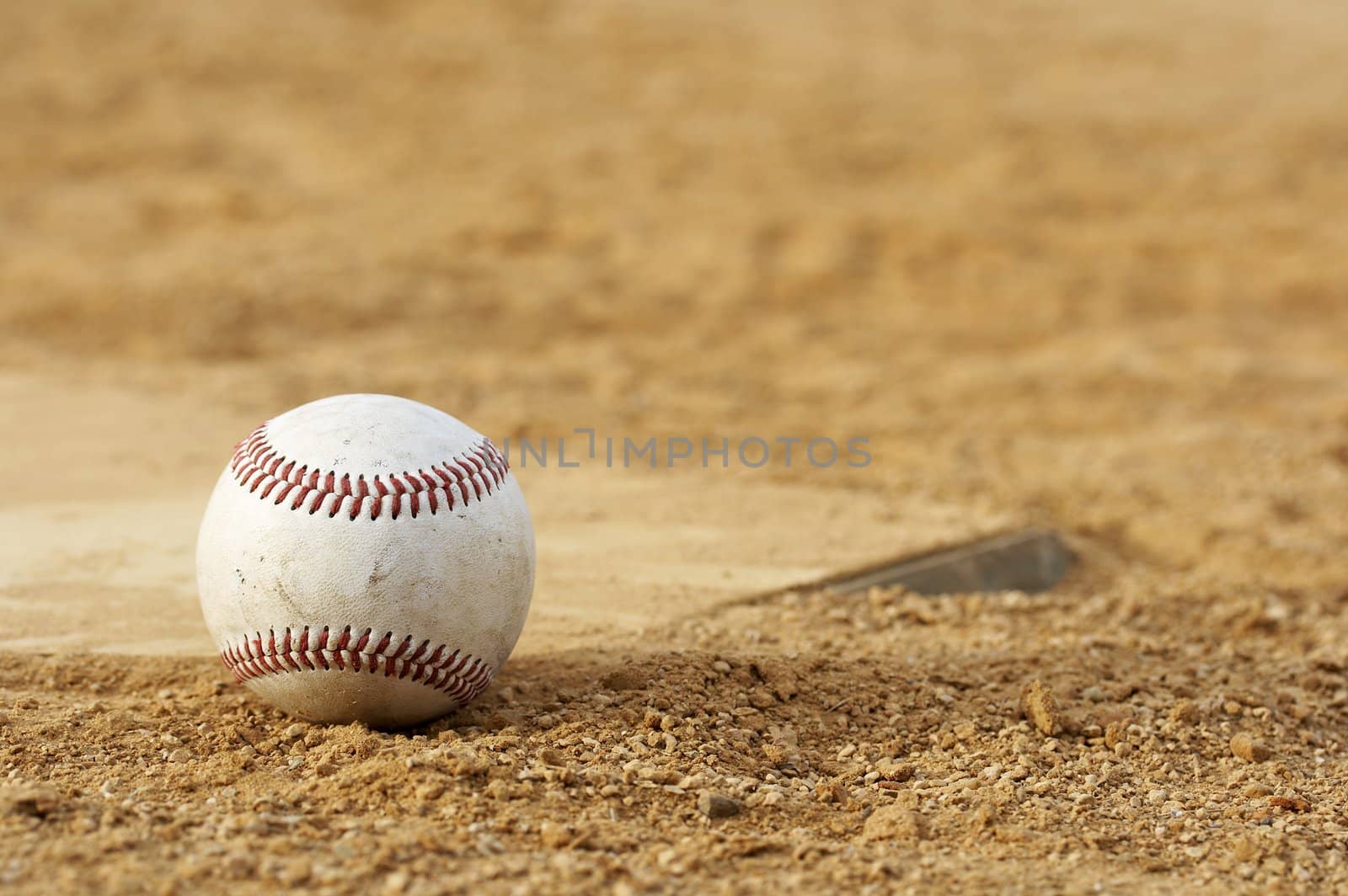 one baseball on home plate at a sports field