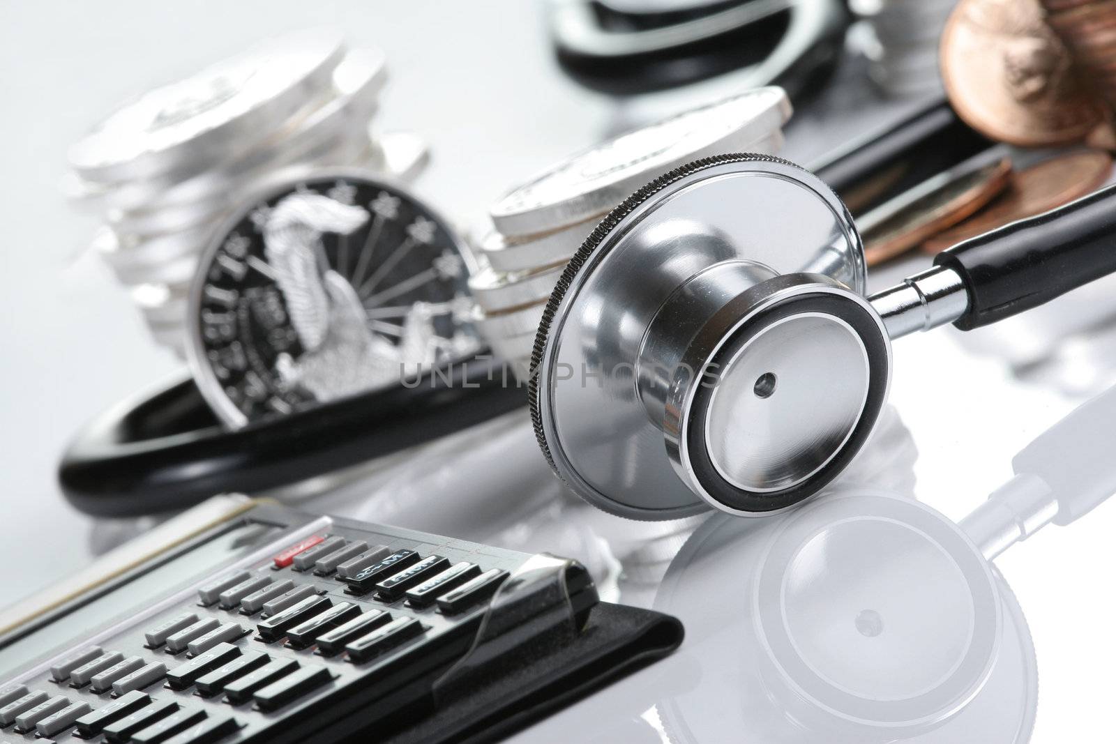 Financial health concept, stethoscope weaving around stacks of silver and gold coins and calculator