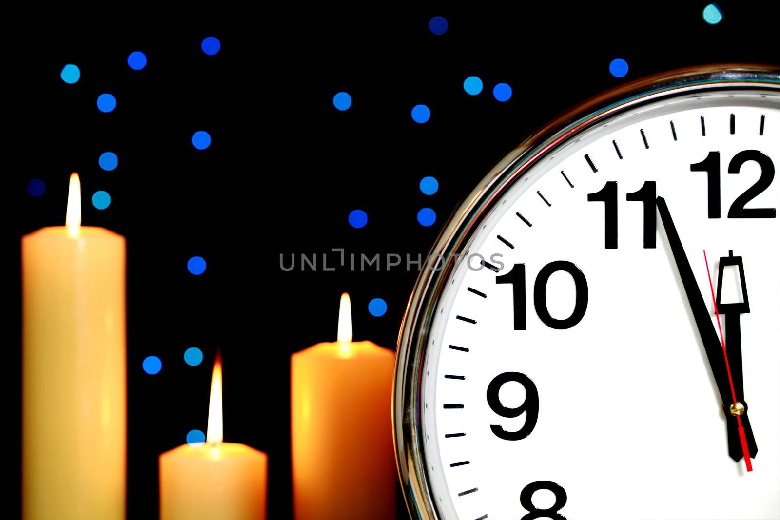 Clock set at three minutes to midnight with blue Christmas lights in background and candles burning