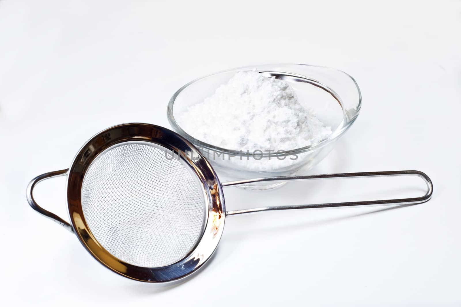 colander and Powdered sugar on white background