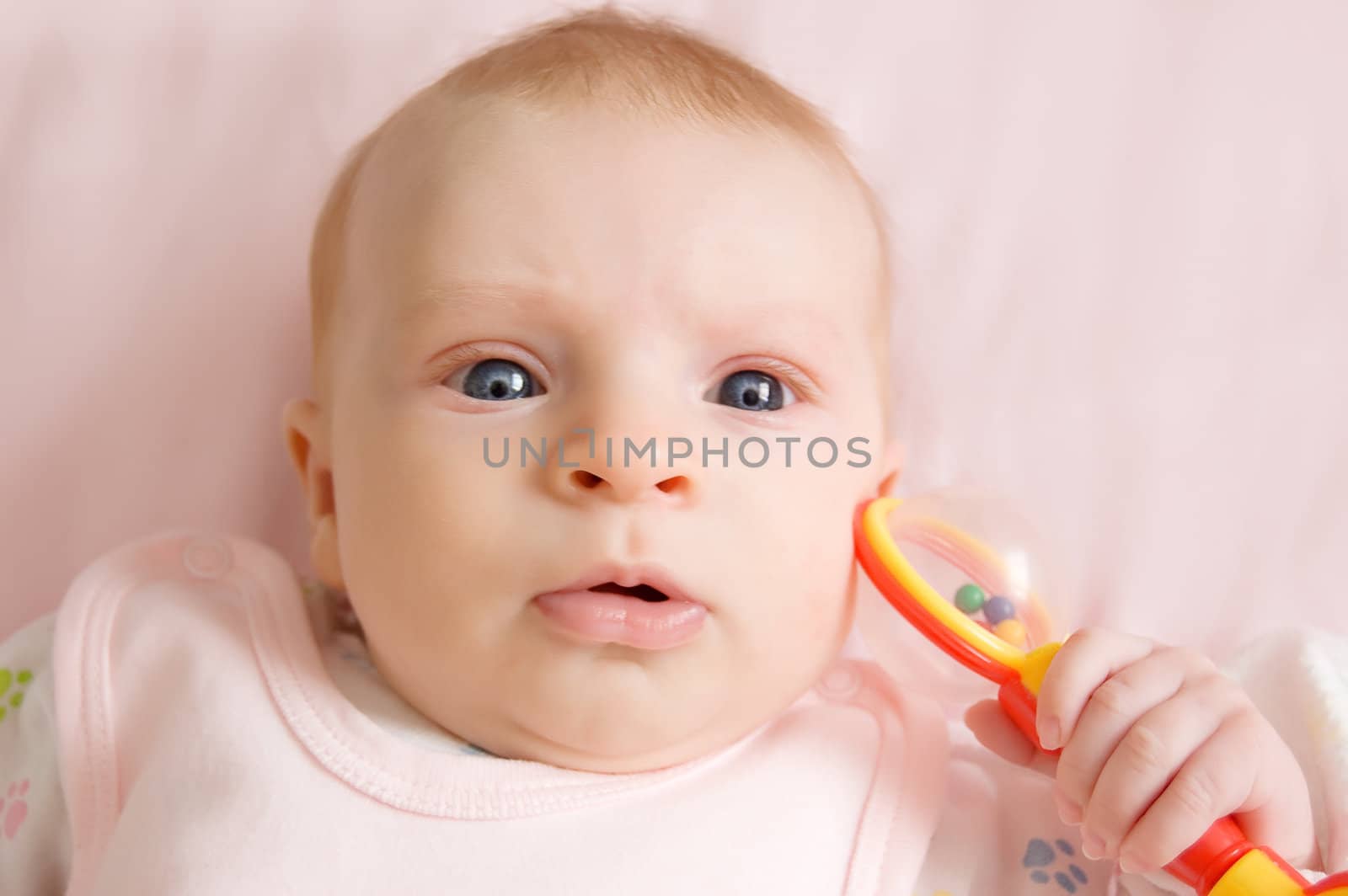 Three months baby girl playing with rattle