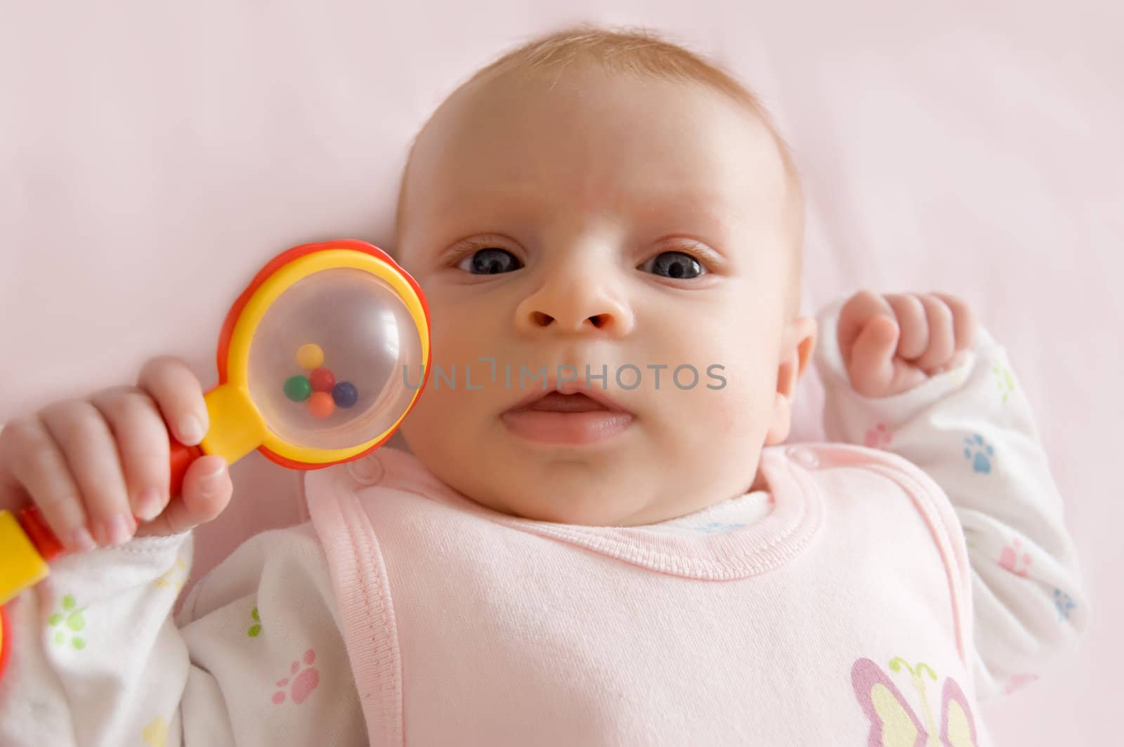 Three months old baby girl holding rattle