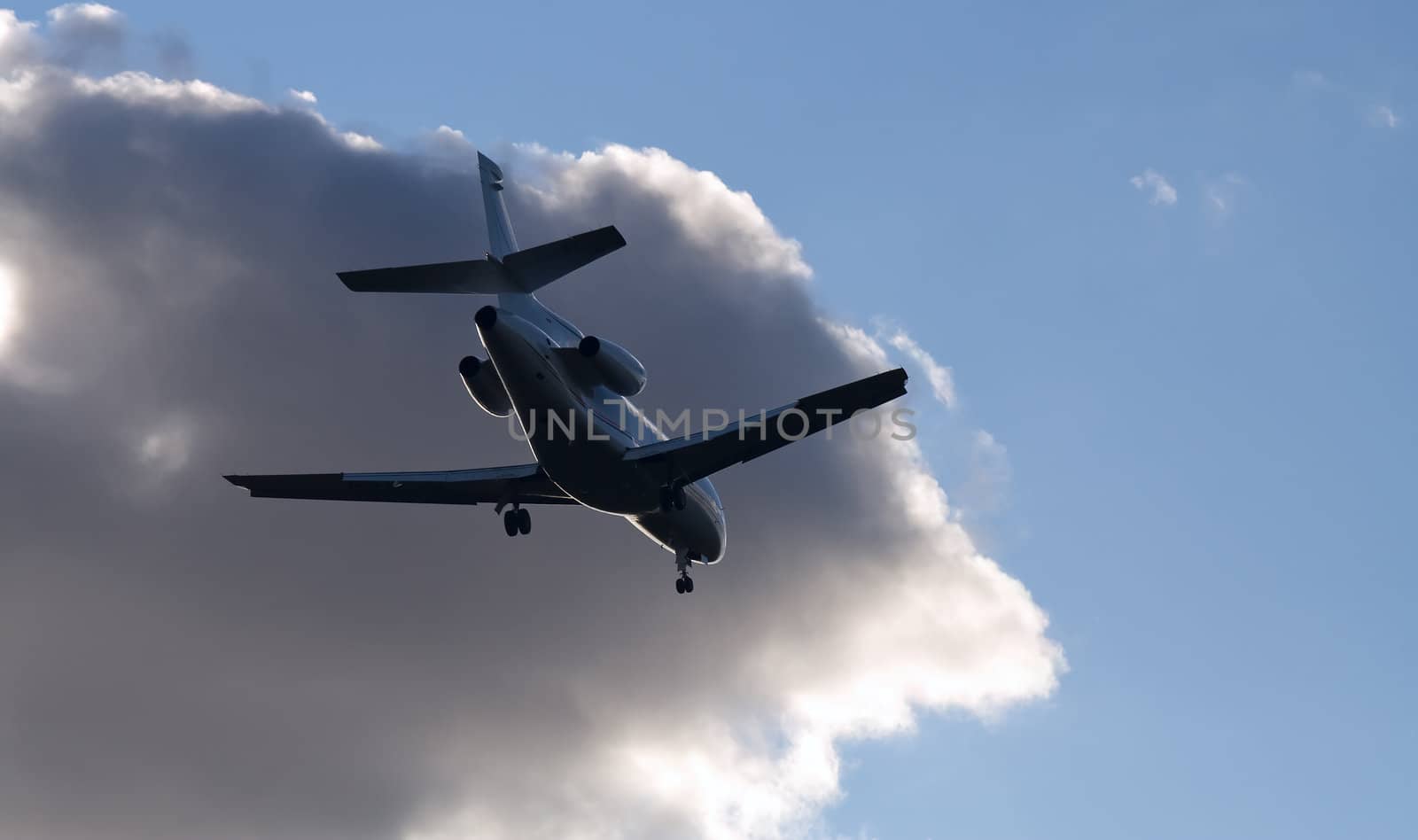 Silhouette of airplane landing on cloud background by serpl