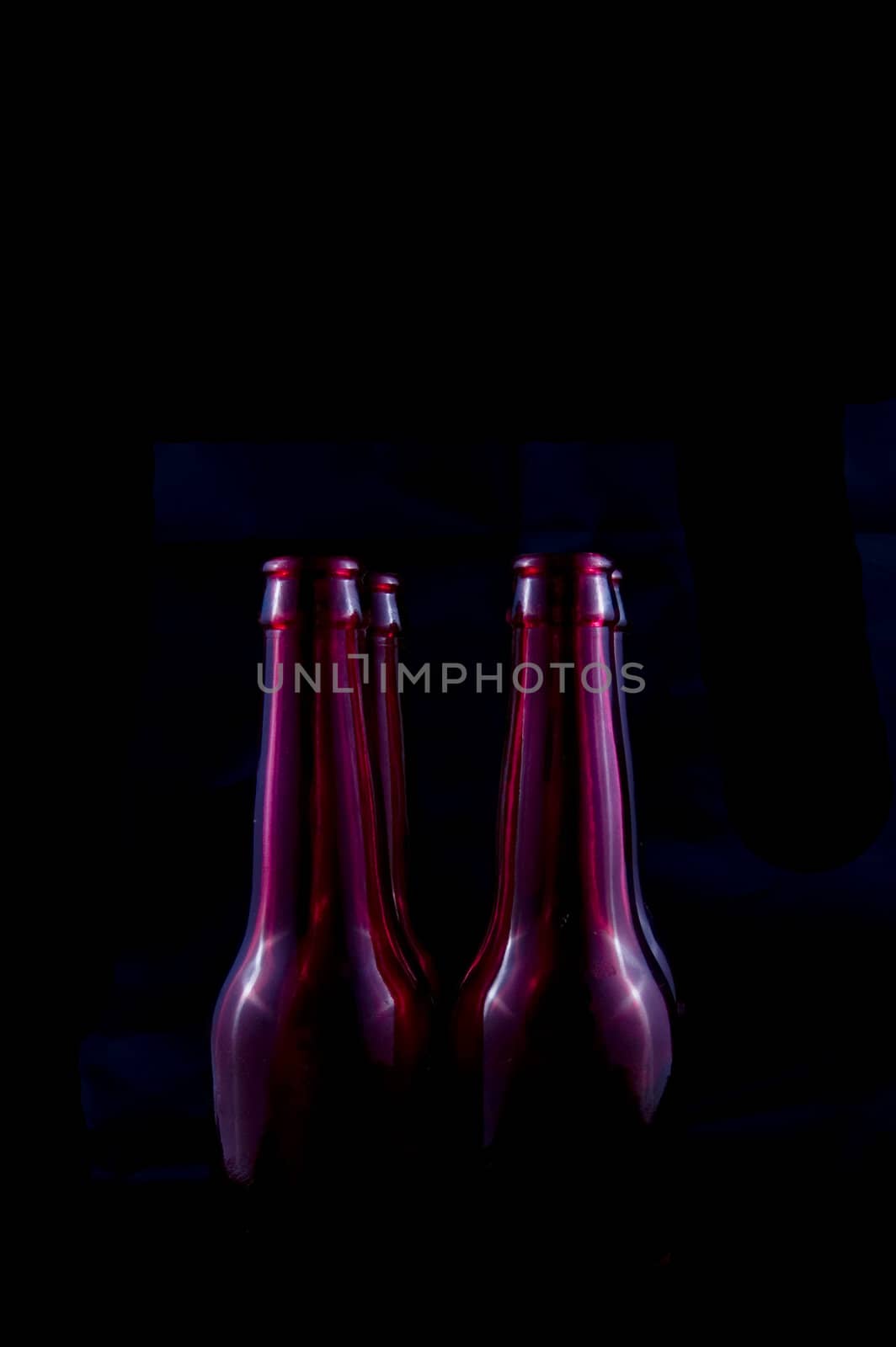 red beer bottles isolated on a black background by ladyminnie