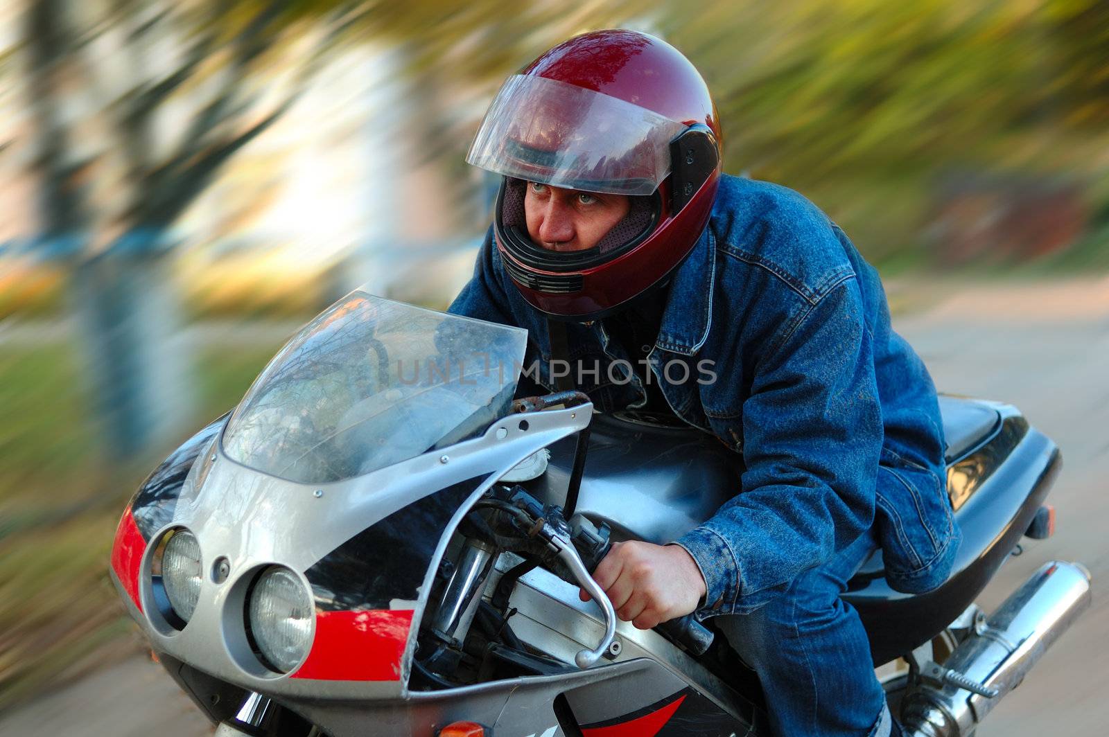 Young man on motorcycle (motorbike) with blurred background (motion blur).