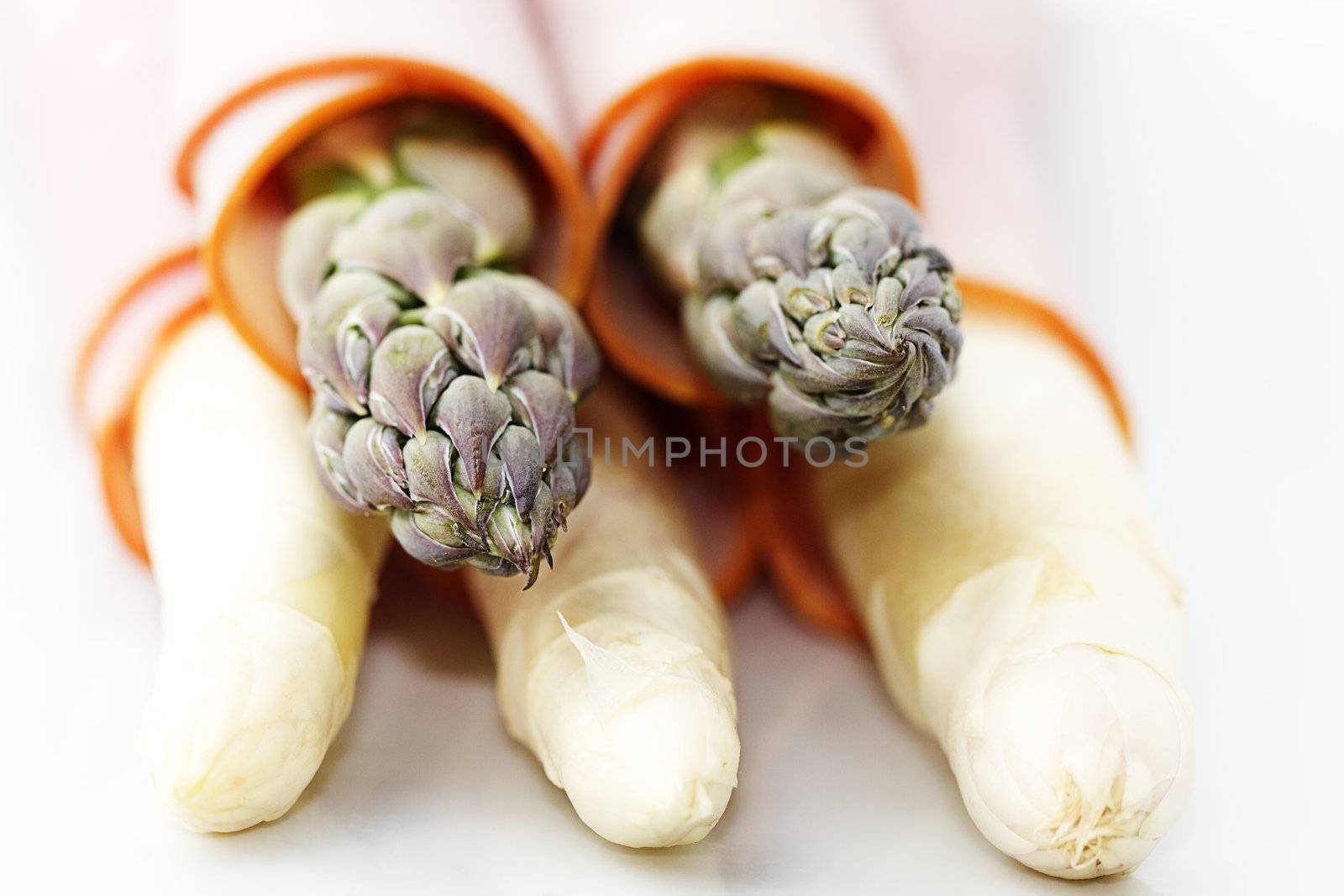 closeup of some green and white asparagus tips enrolled with ham