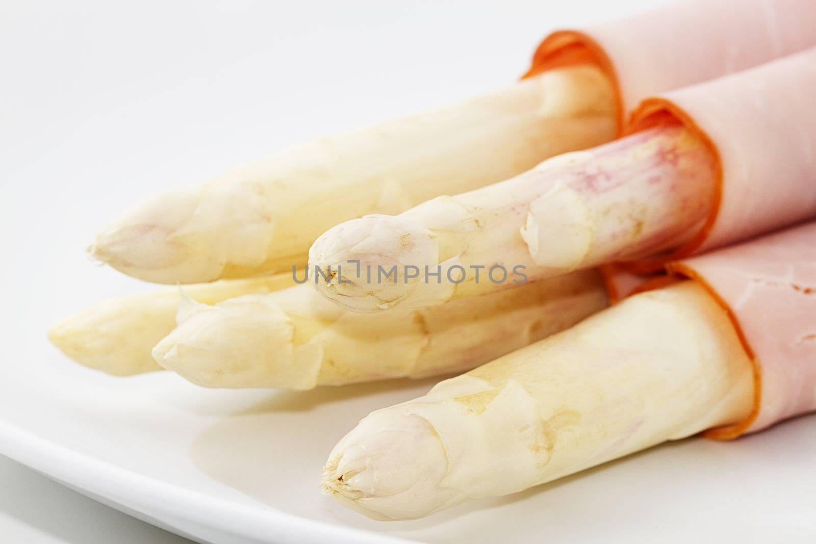 some asparagus enrolled with ham on a white plate