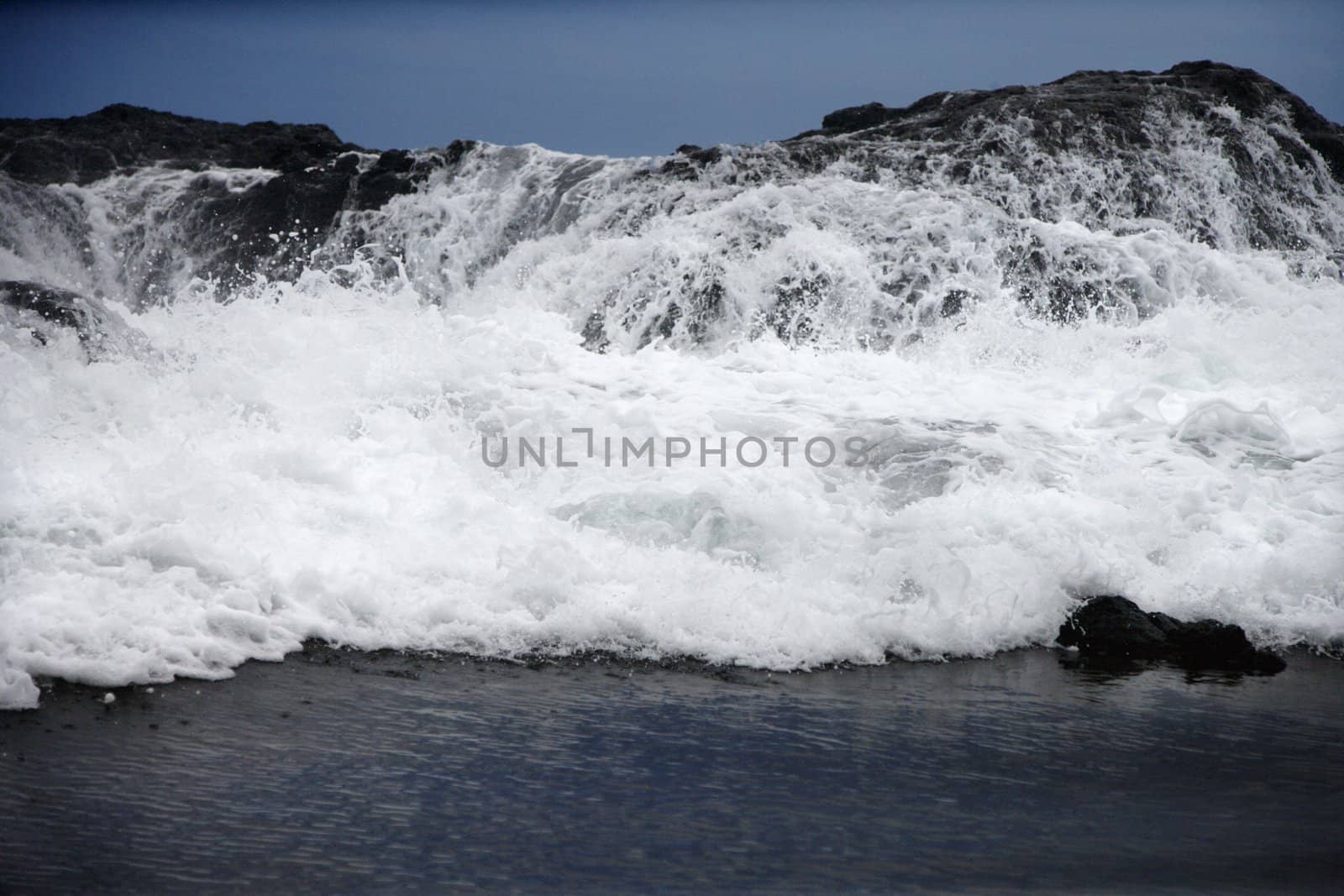 Landscape of waves crashing into rocky Maui Hawaii coast.