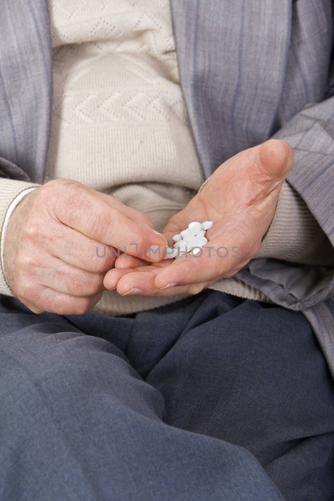 Close-up image of a senior's hands taking pills.