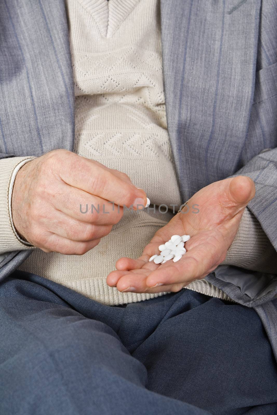 Close-up image of a senior's hands taking pills.