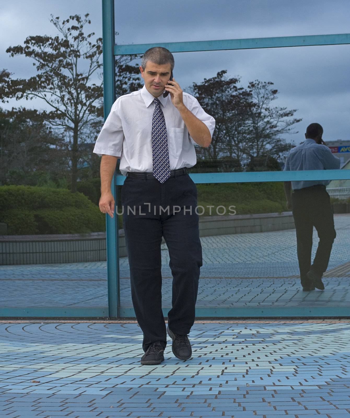Businessman using a mobile phone in front of a corporate building.