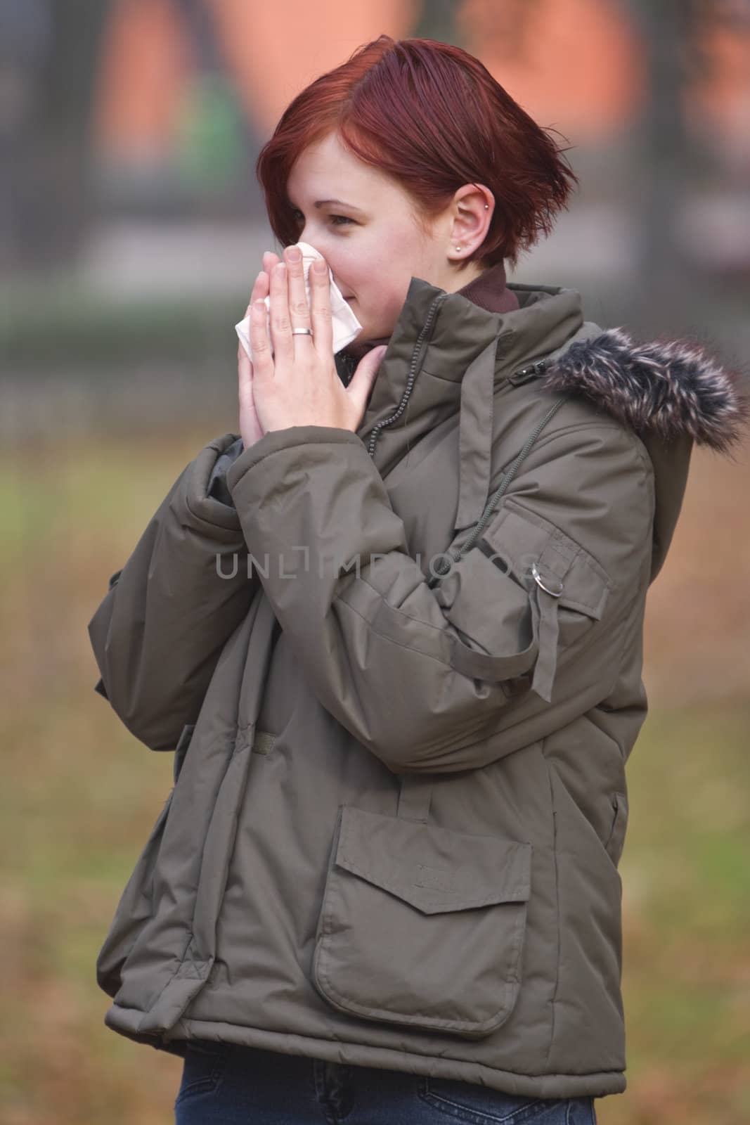 Girl blowing her nose outdoors in late autumn.