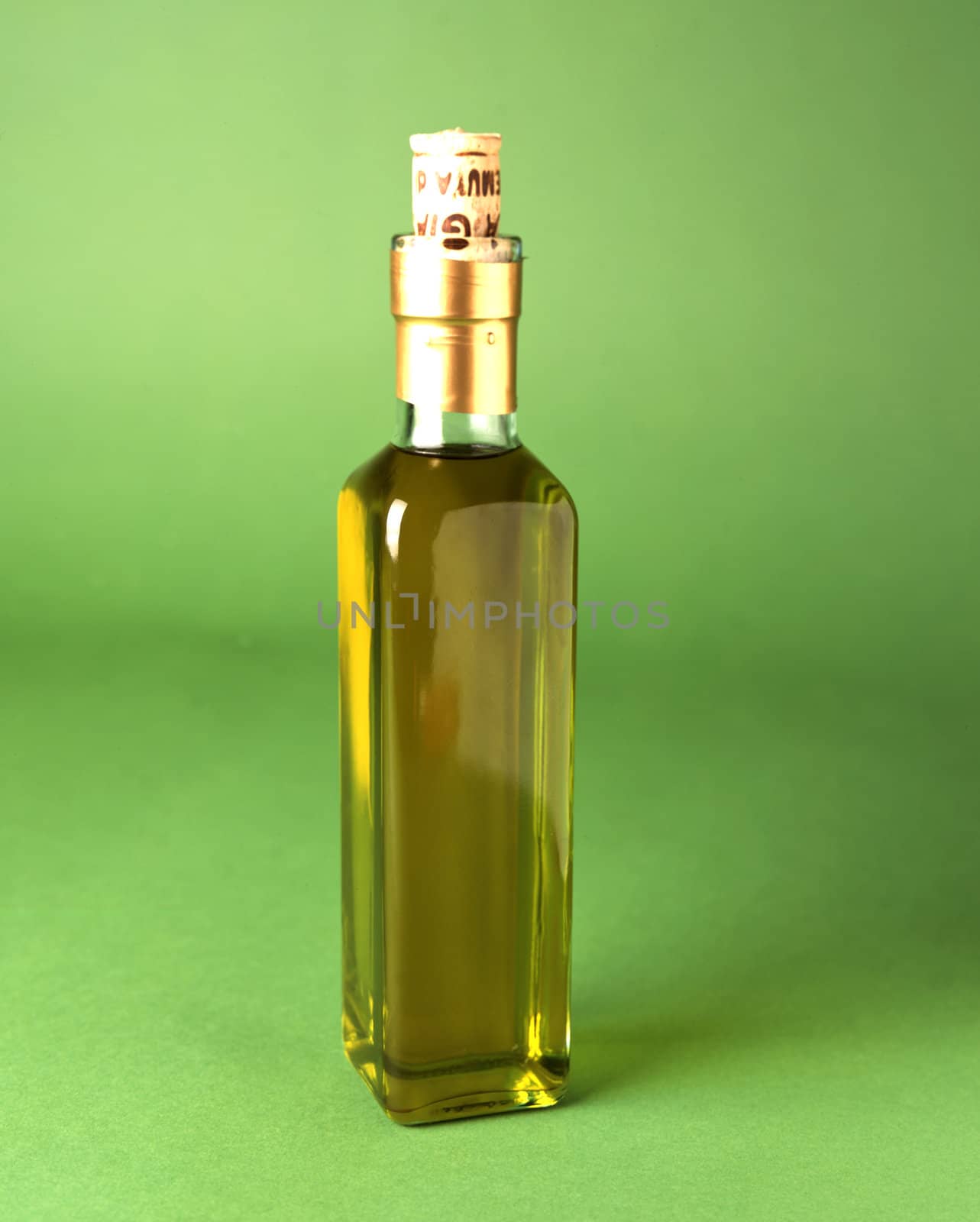 Glass bottle of olive oil with cork on green
