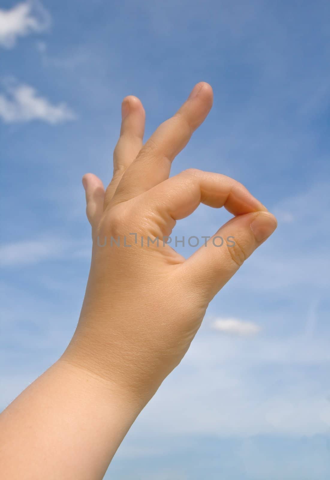 Human hand making OK sign against blue sky