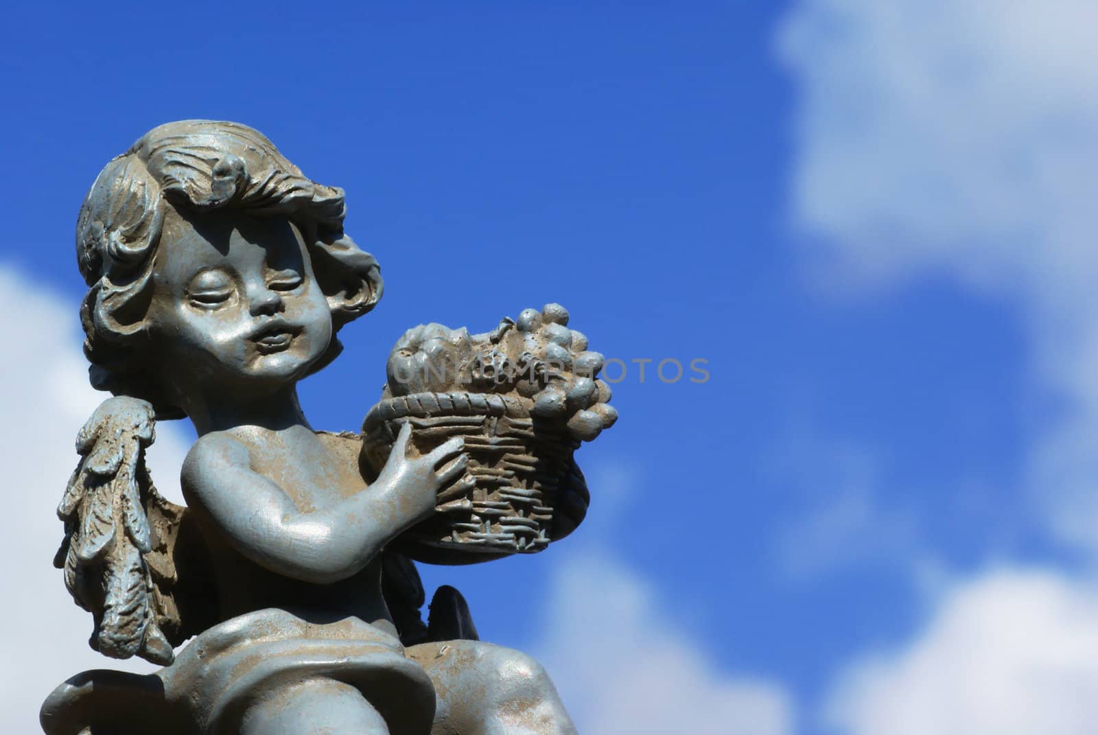 Little angel statue against a blue cloudy sky.