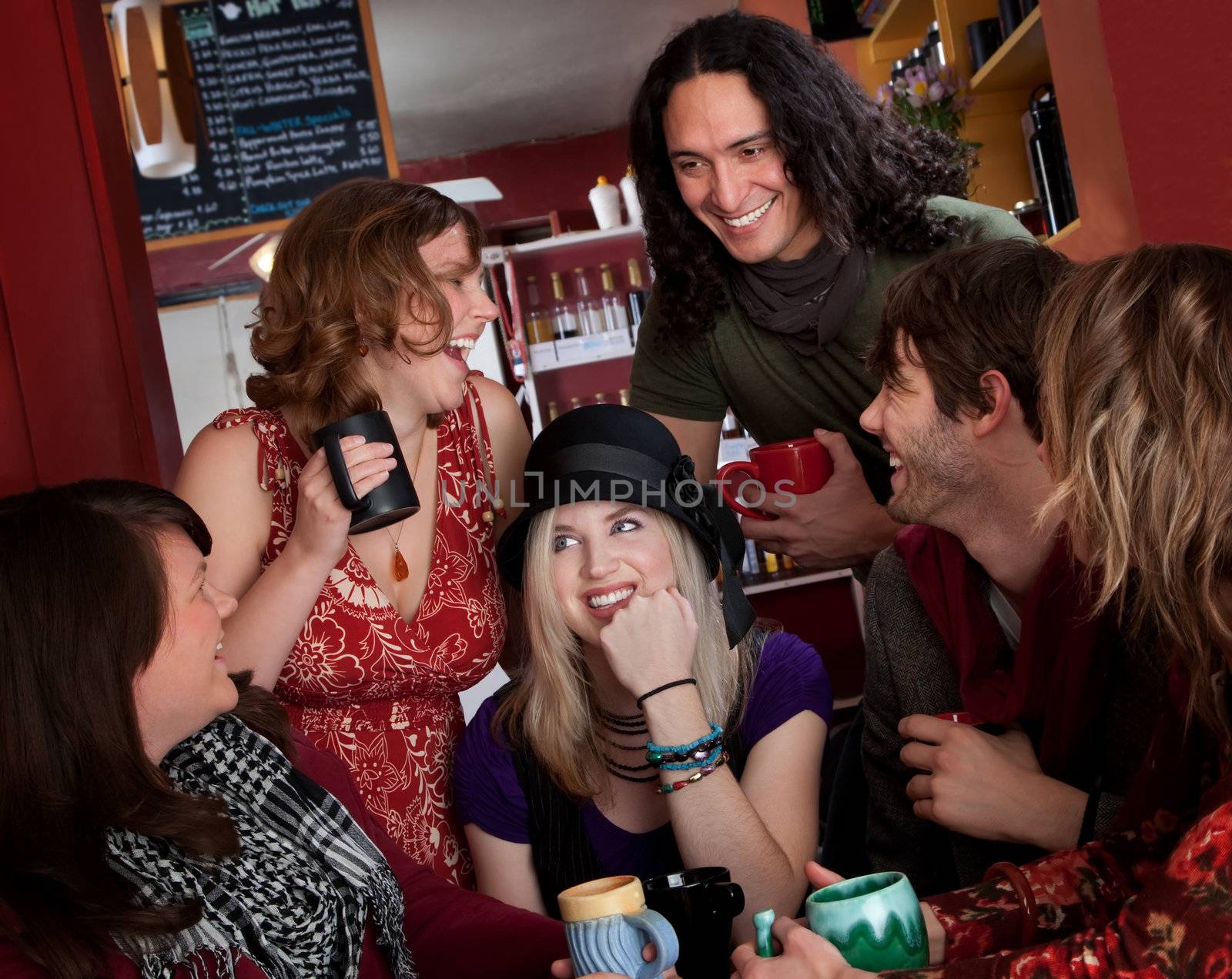 Group of six friends laughing over coffee