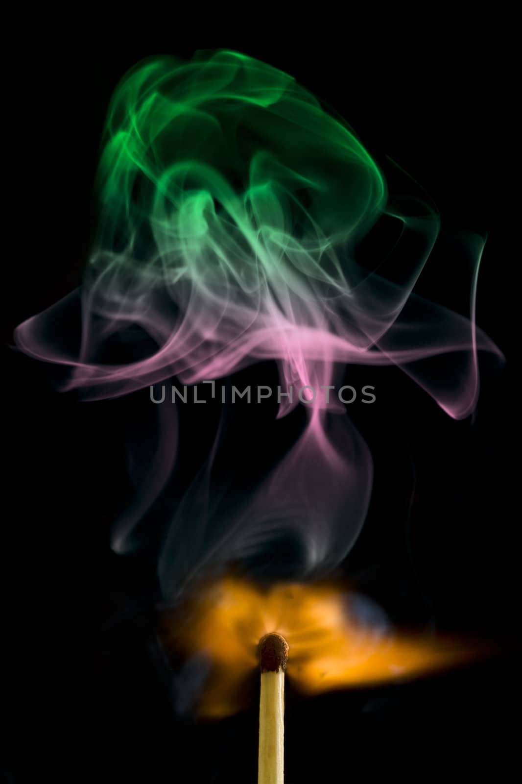 Magic matchstick with colorful smoke over black background