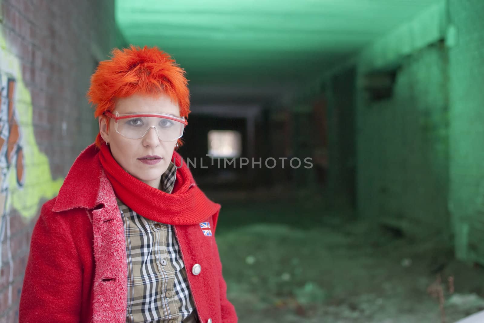 Red-haired woman stands near the entrans of the greenish tunnel.