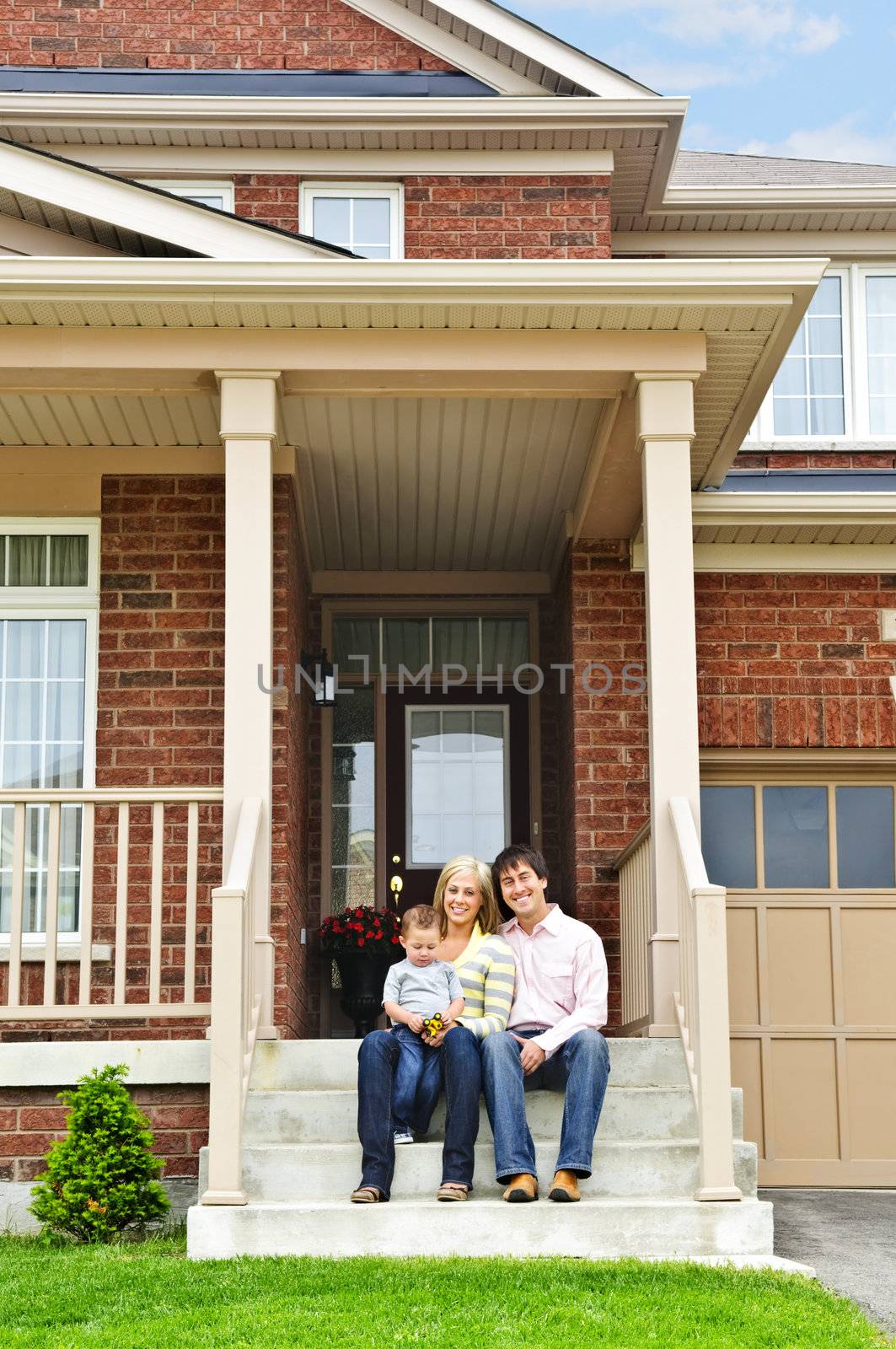 Young family sitting on front steps of house